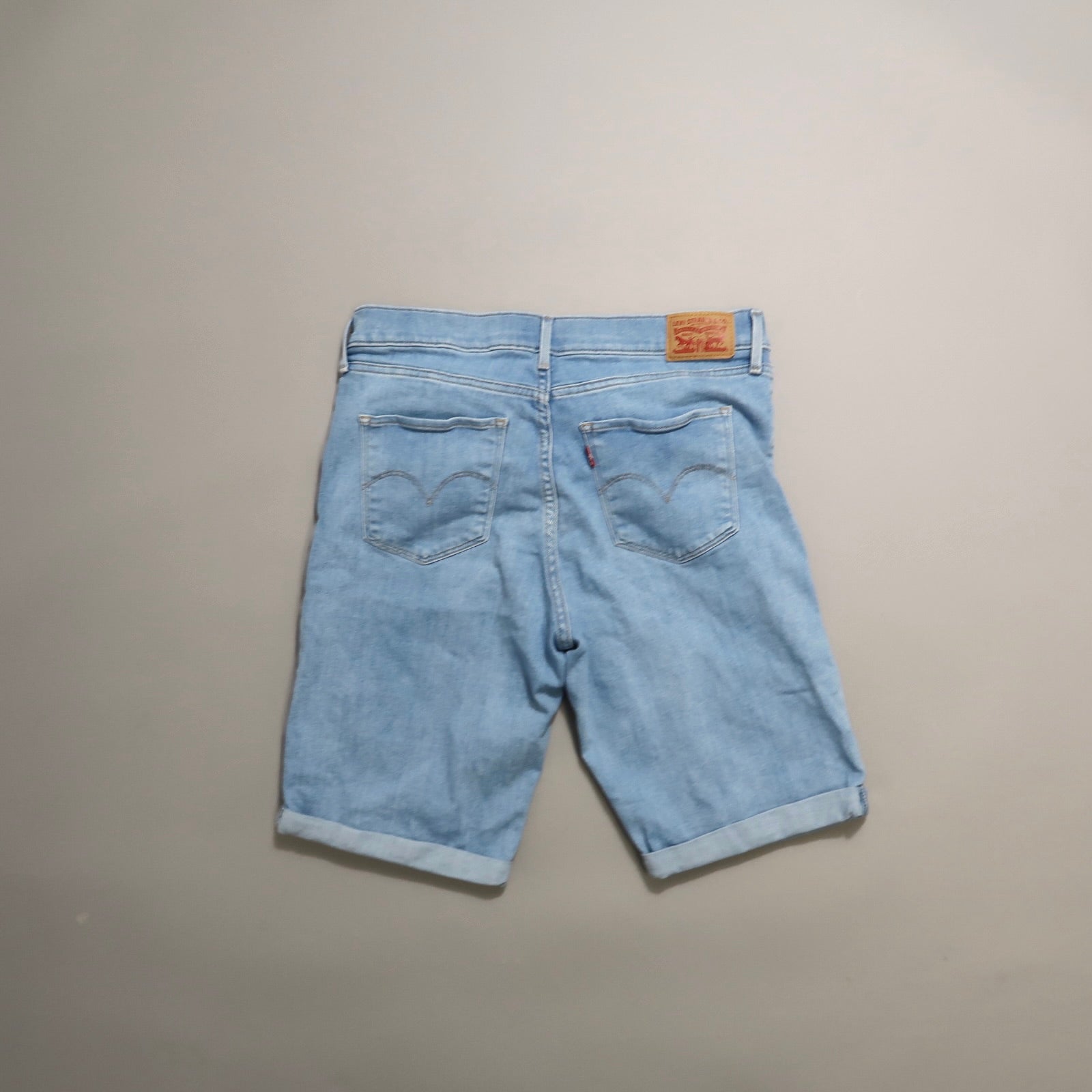 Back view of light blue denim shorts with rolled cuffs.