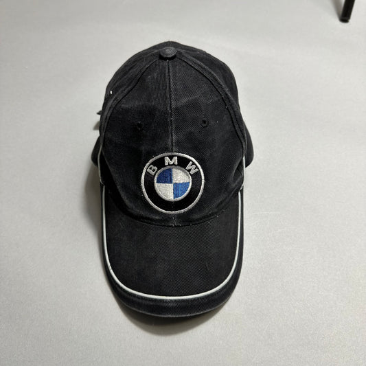 Black baseball cap with BMW logo on a gray background.