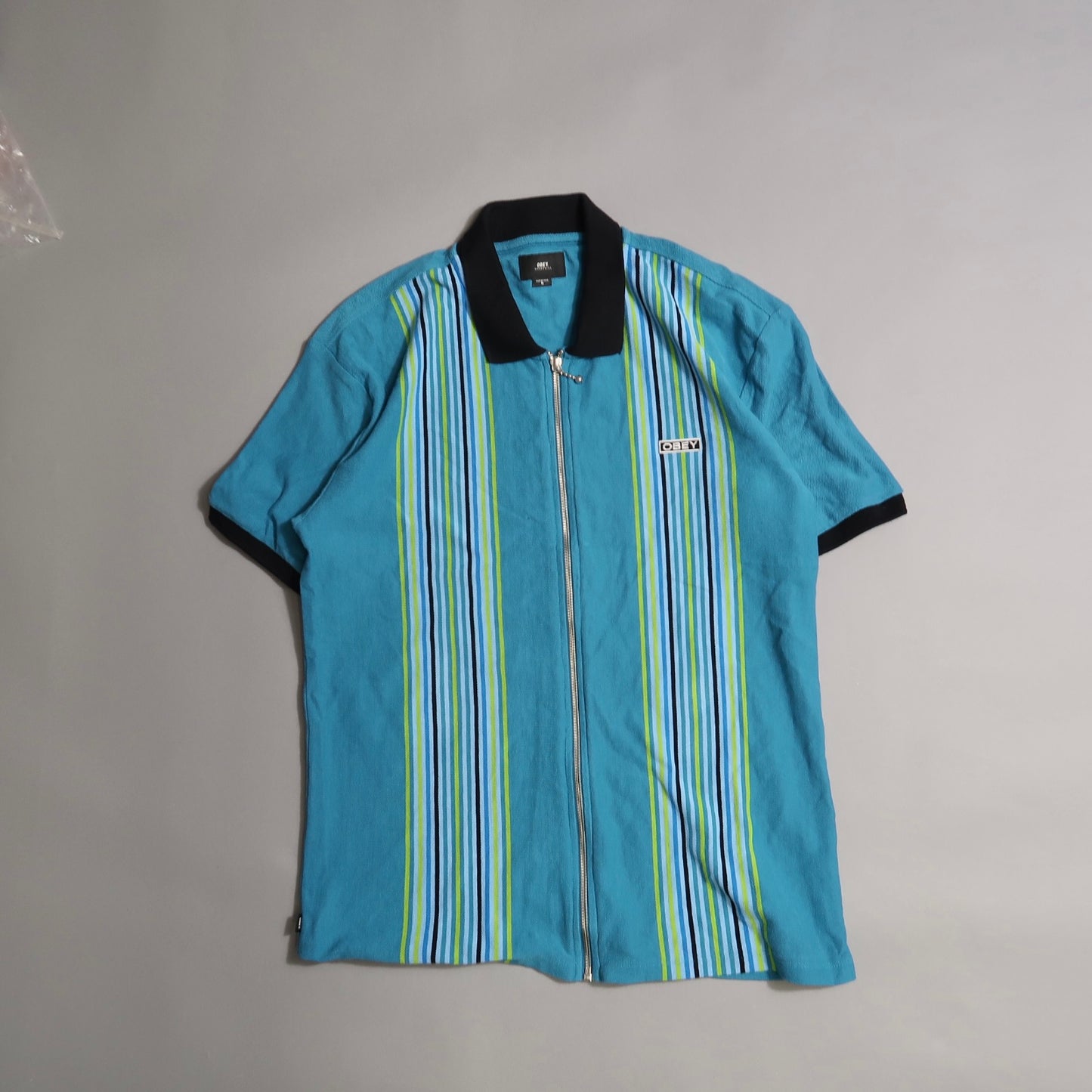 Blue zip-up shirt with vertical green and white stripes.