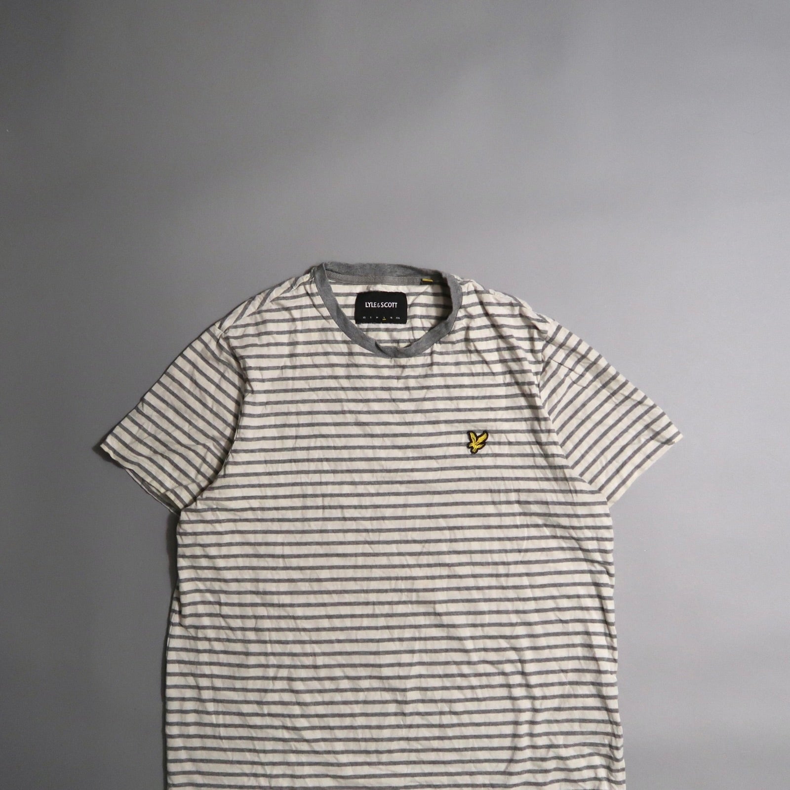 Striped T-shirt with small yellow logo on chest, laid on a flat surface.