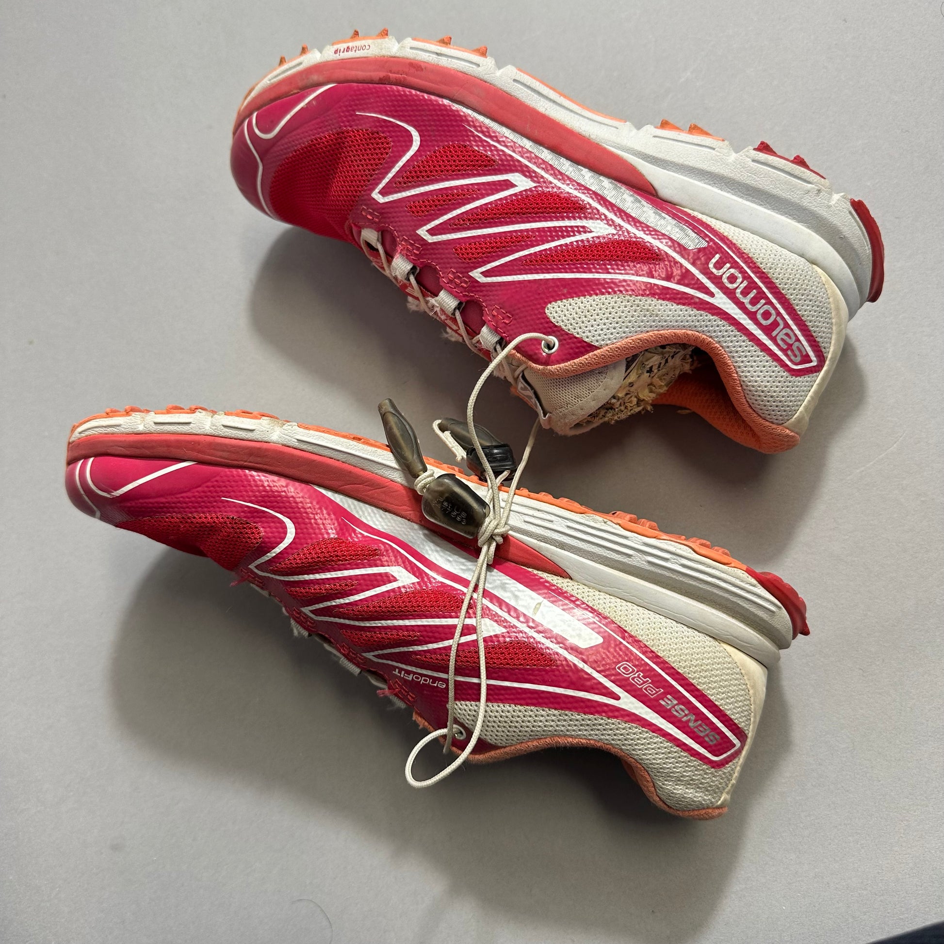 Red and white trail running sneakers with worn soles.