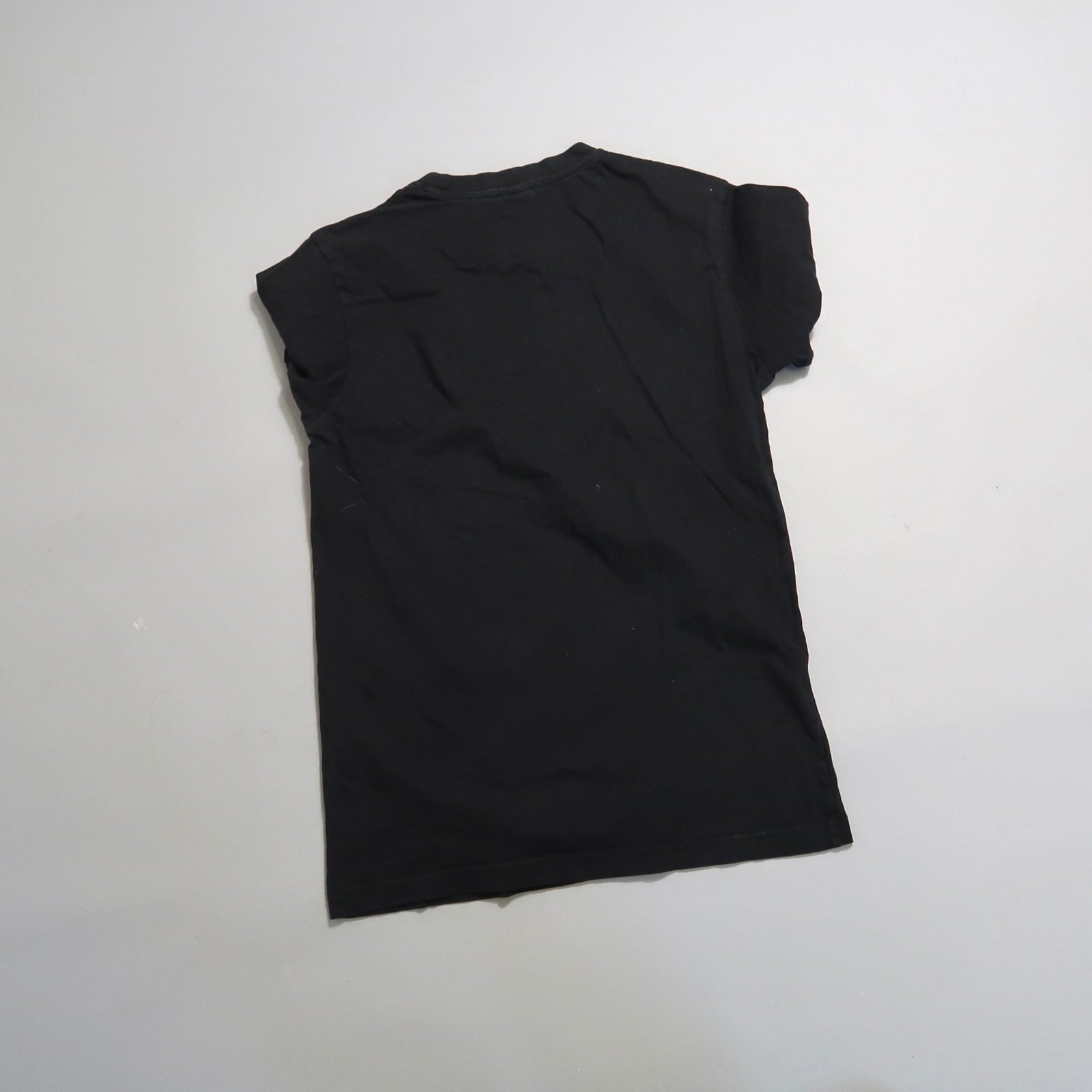 Black t-shirt laid flat on a light gray background.