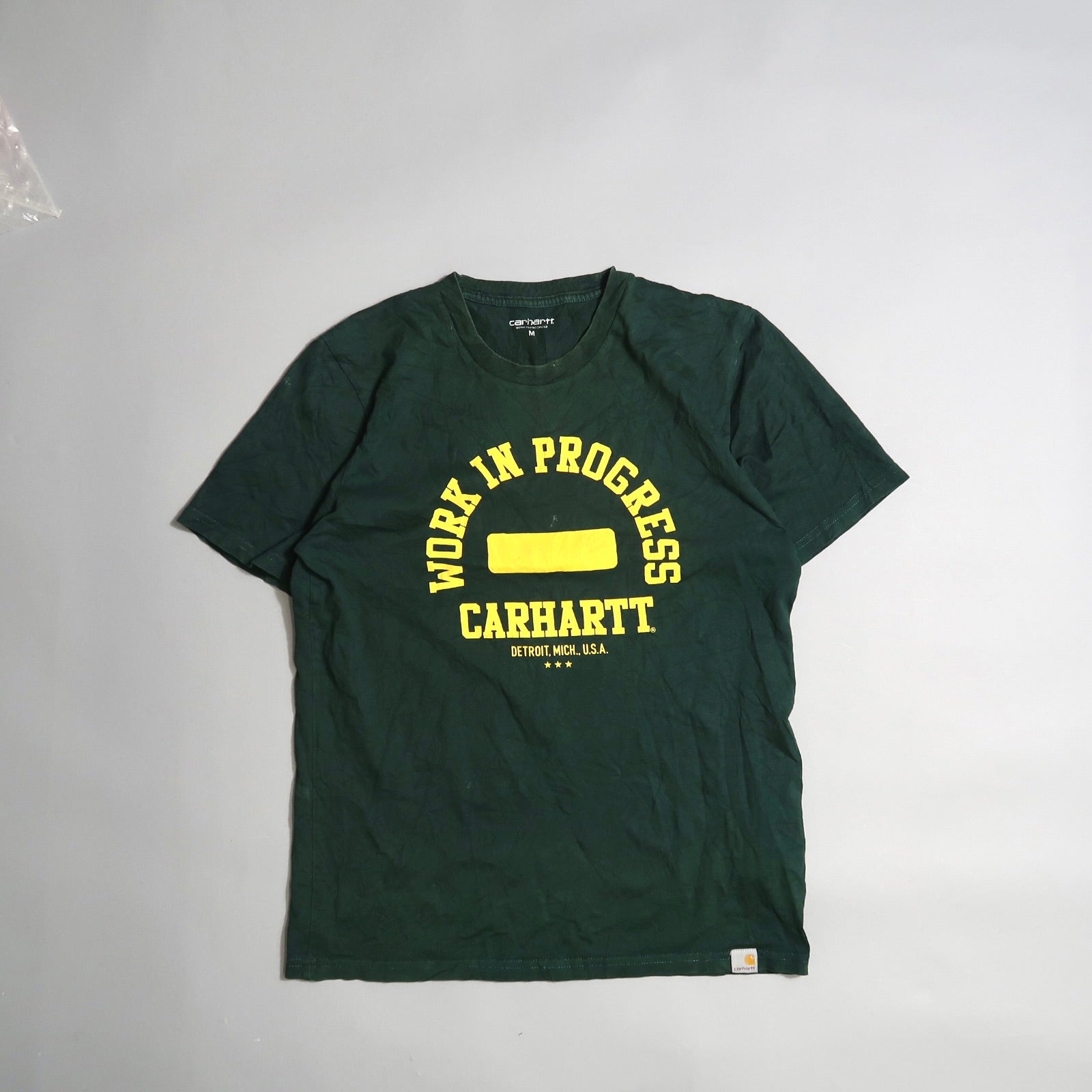 Green Carhartt T-shirt with yellow nullWork in Progressnull text.
