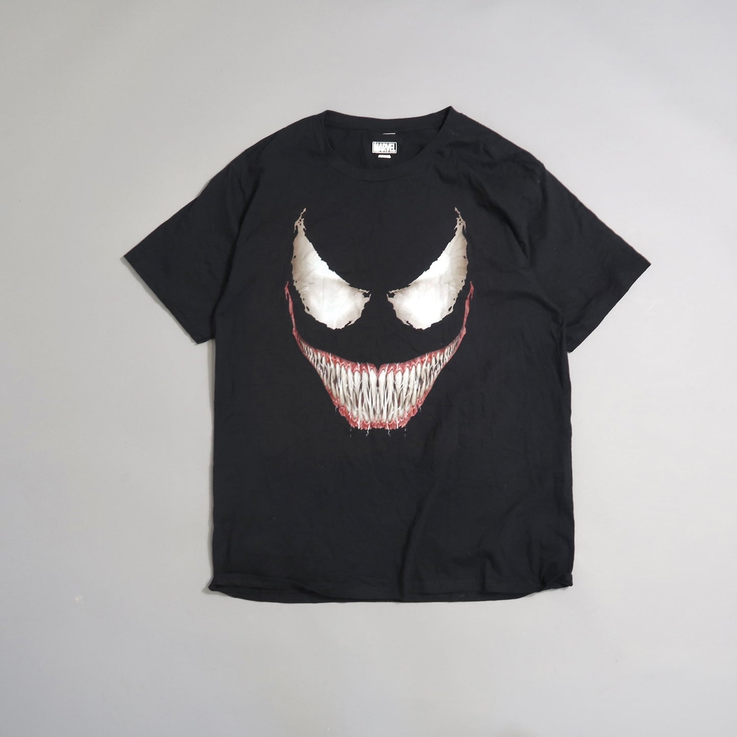 Black T-shirt featuring a sinister white and red grinning face design.