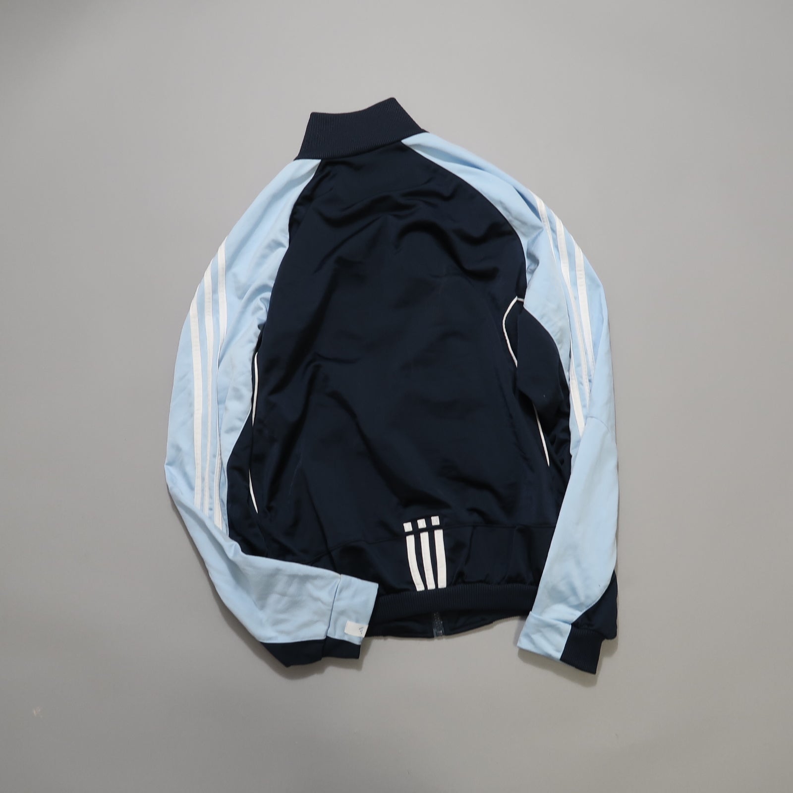 Blue and black jacket with white stripes on a gray background.