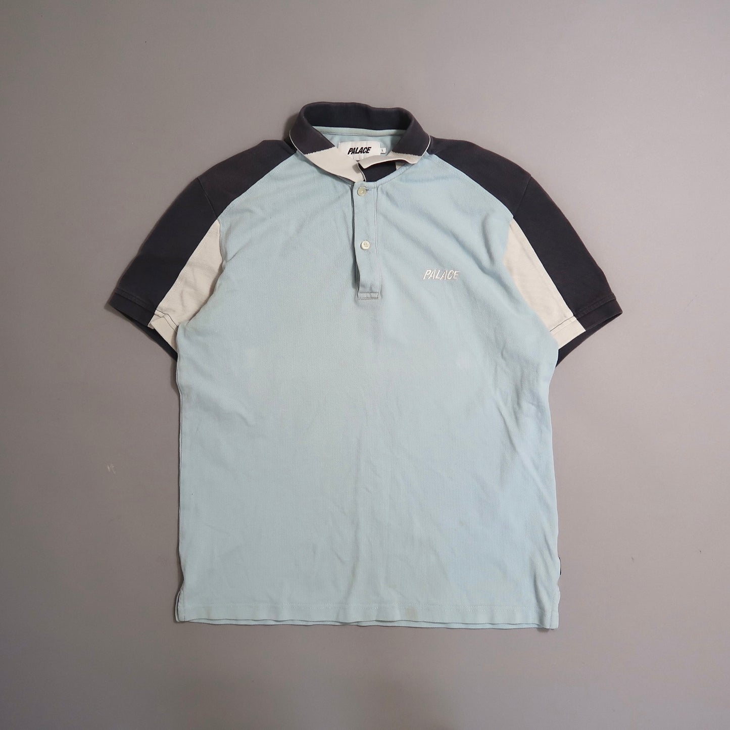 Light blue and black polo shirt with nullPalacenull text on chest.