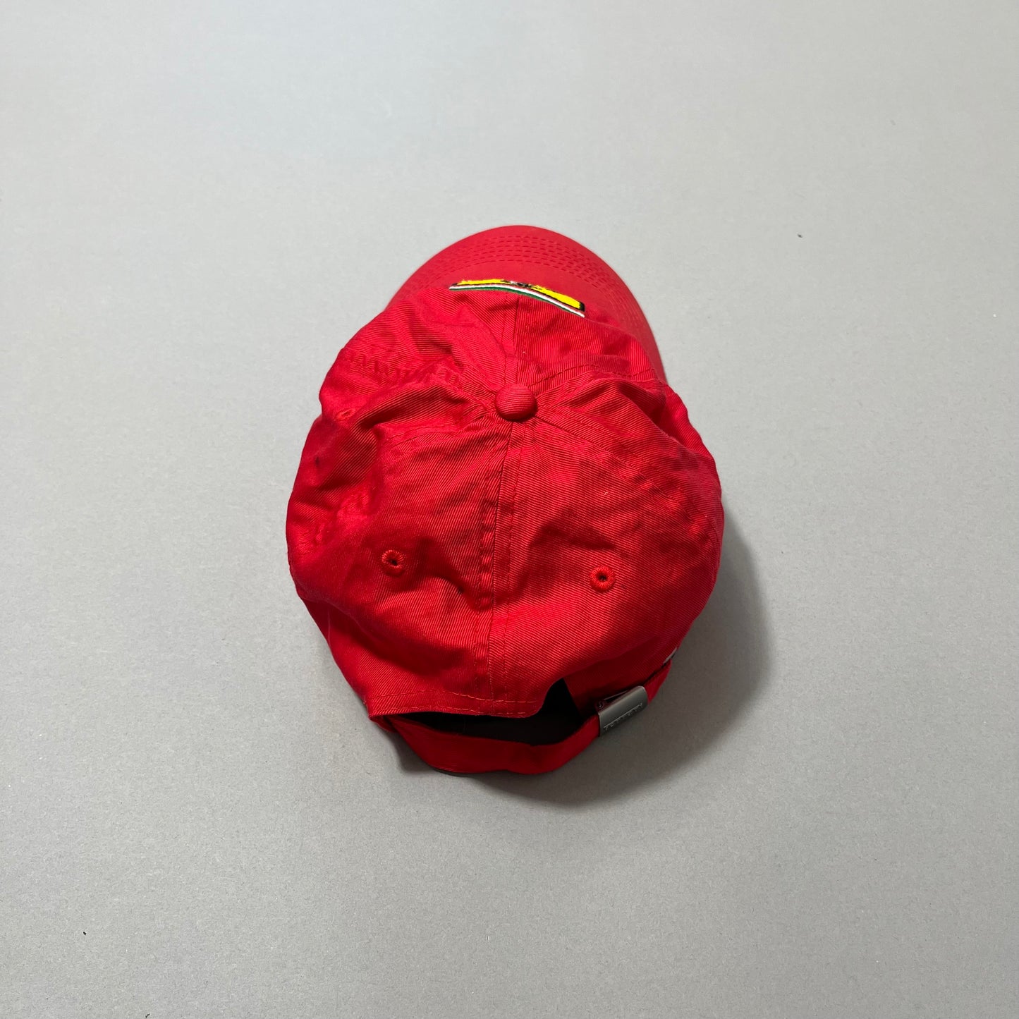 Red baseball cap upside down on a gray surface.