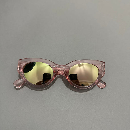 Pink cat-eye sunglasses with reflective lenses on a gray surface.