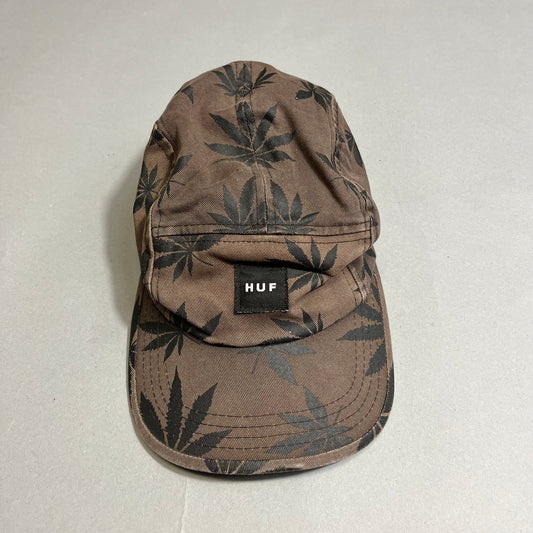 Brown HUF cap with black leaf pattern on a gray background.