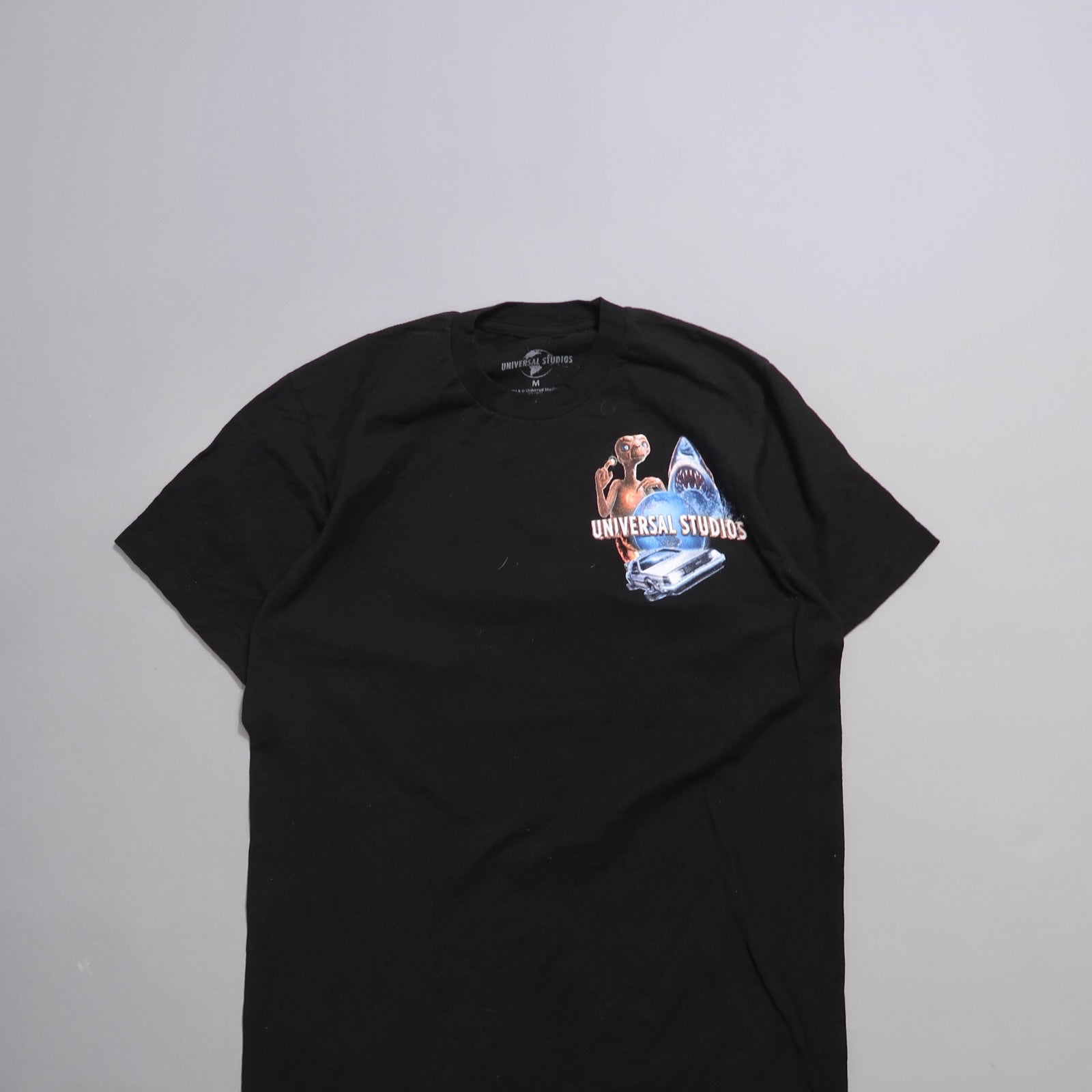 Black T-shirt with Universal Studios graphic including shark and alien.