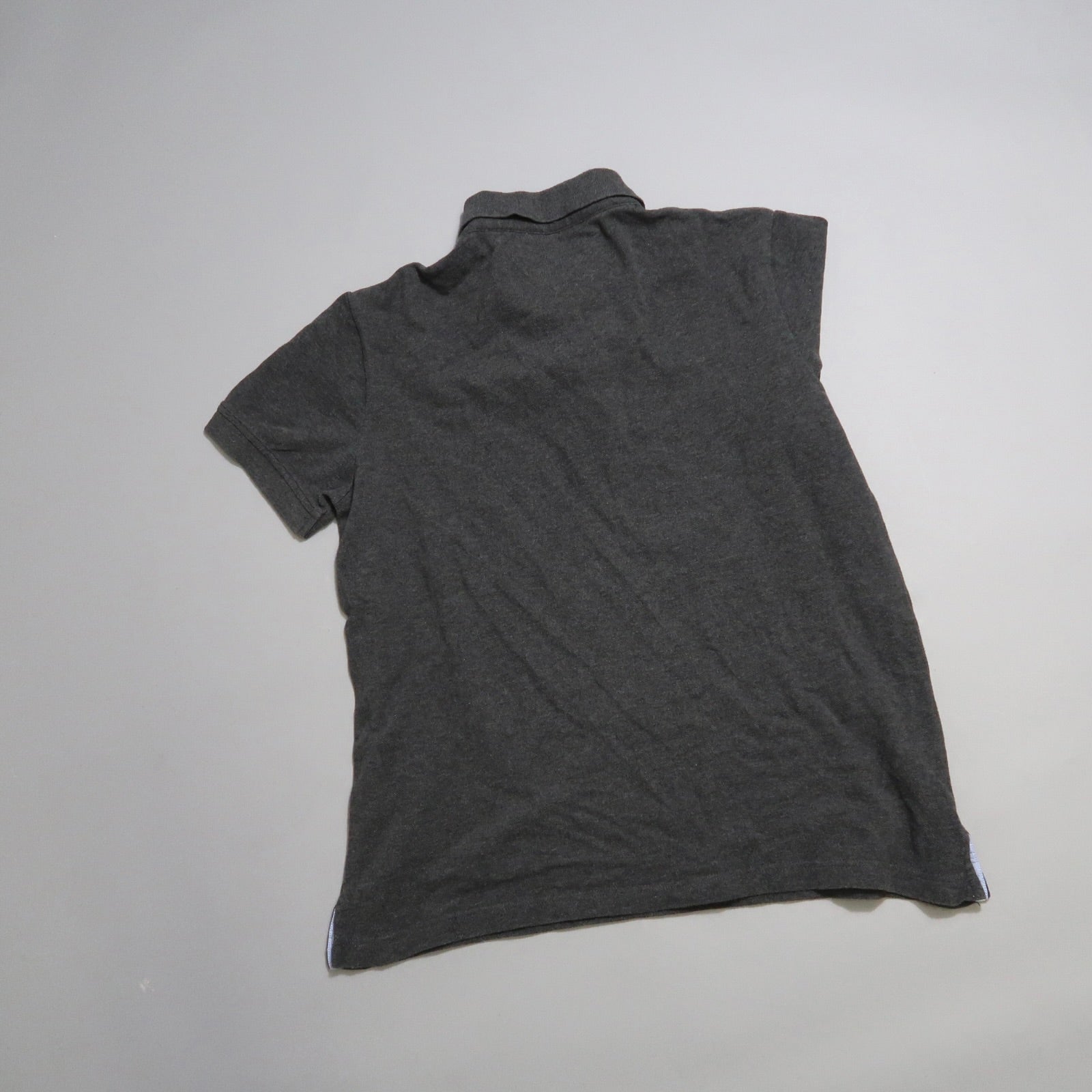 Dark gray polo shirt lying flat on a light surface.