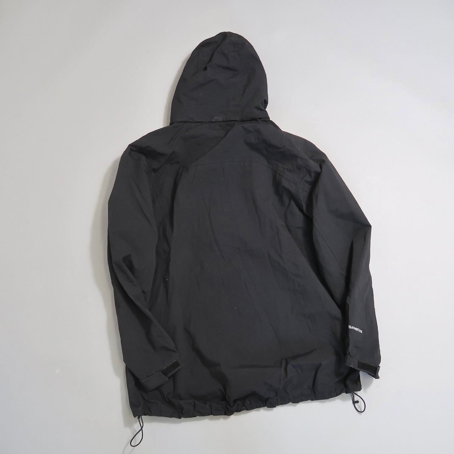 Black hooded jacket viewed from the back on a plain background.