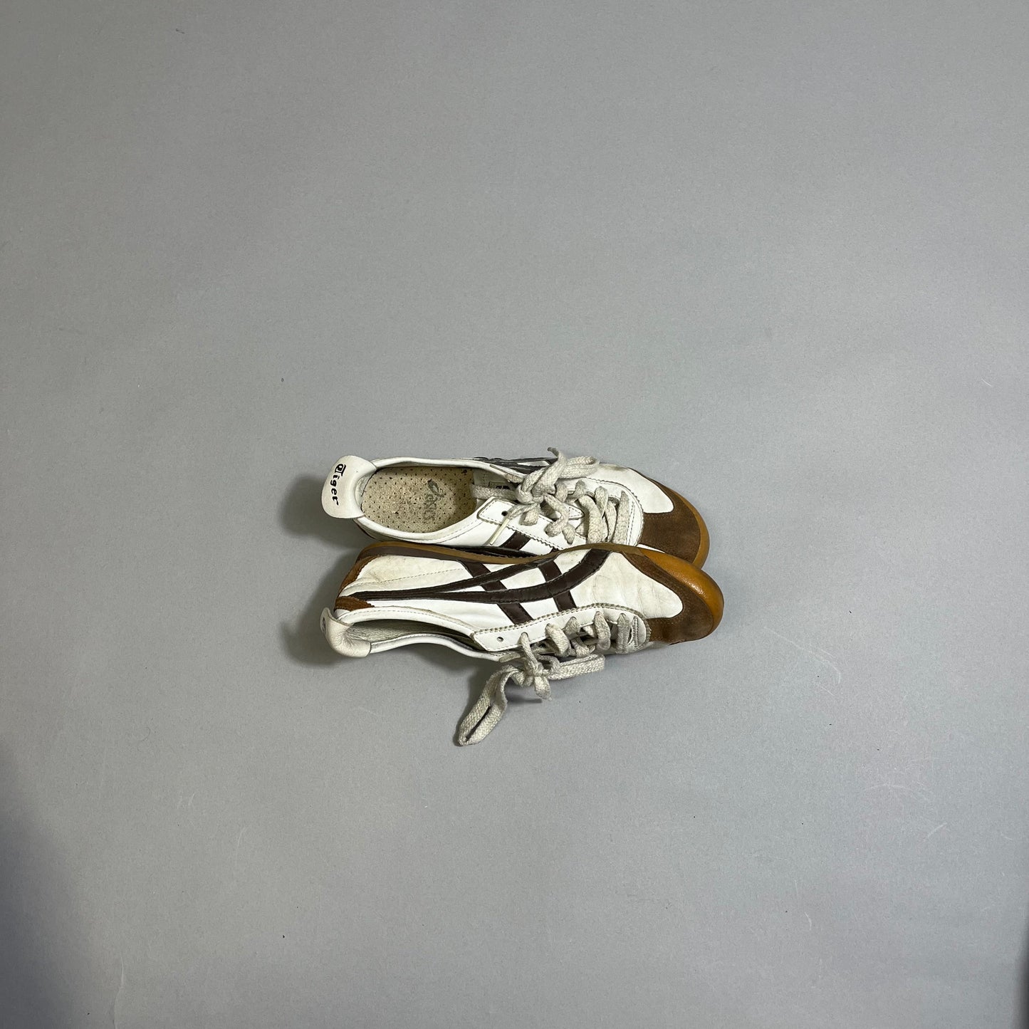 White sneakers with black stripes on a gray background.