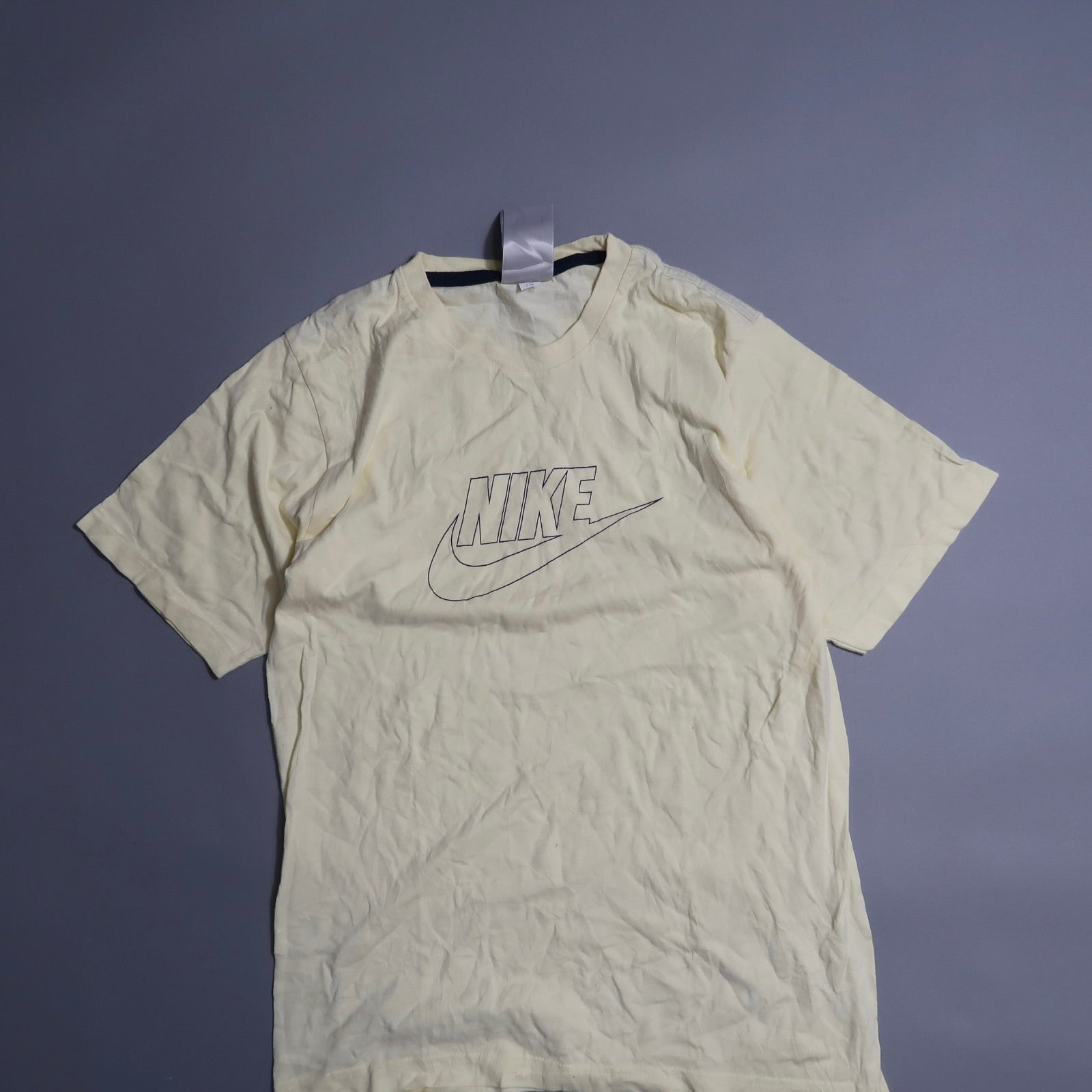 Cream Nike T-shirt with logo on plain background.