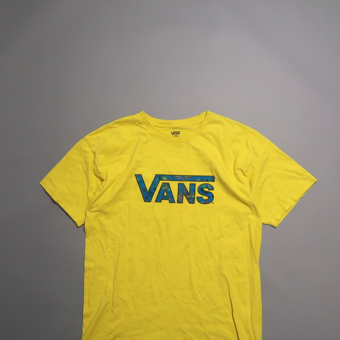 Yellow Vans T-shirt with blue logo, laid flat on a gray background.