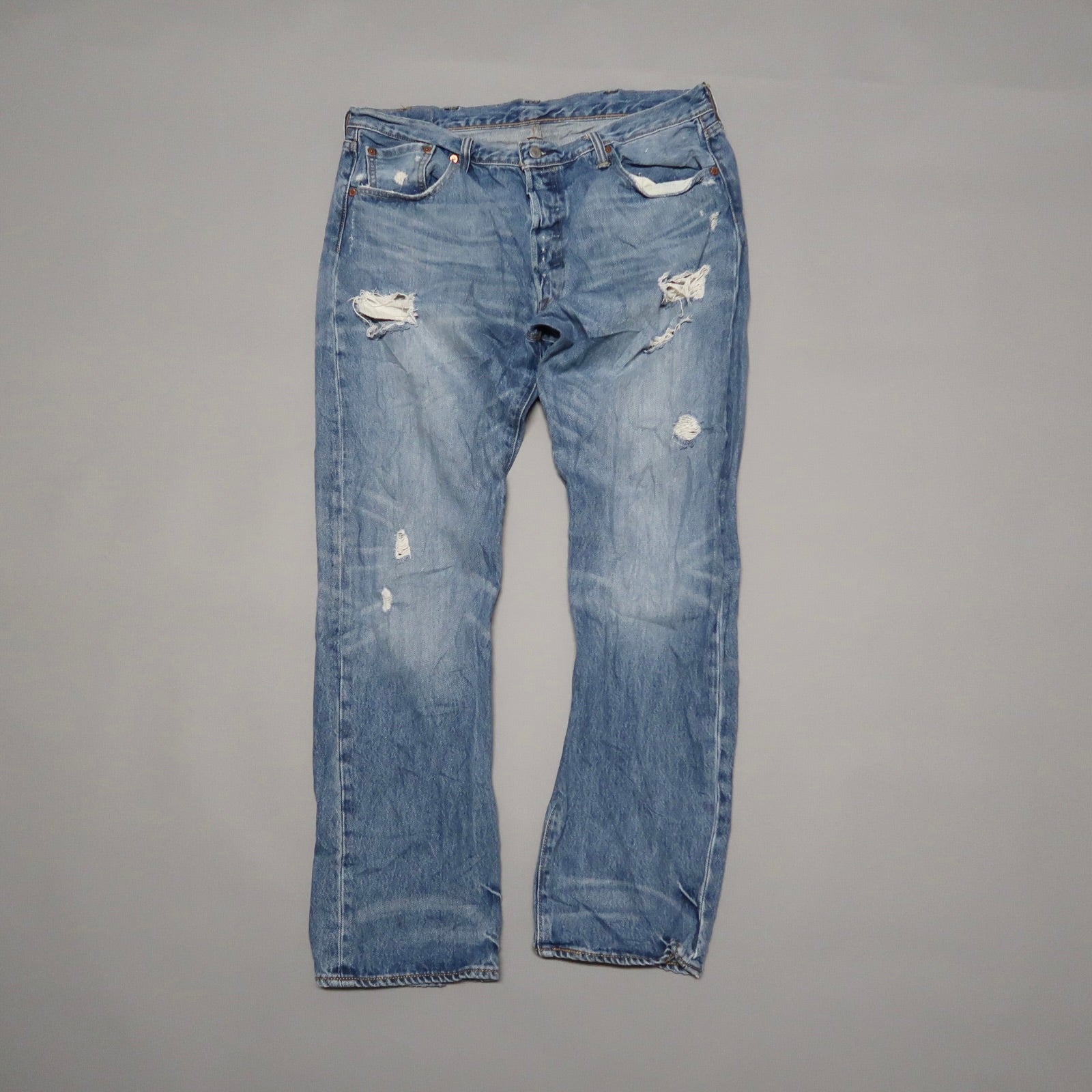 Distressed blue jeans with several ripped patches.