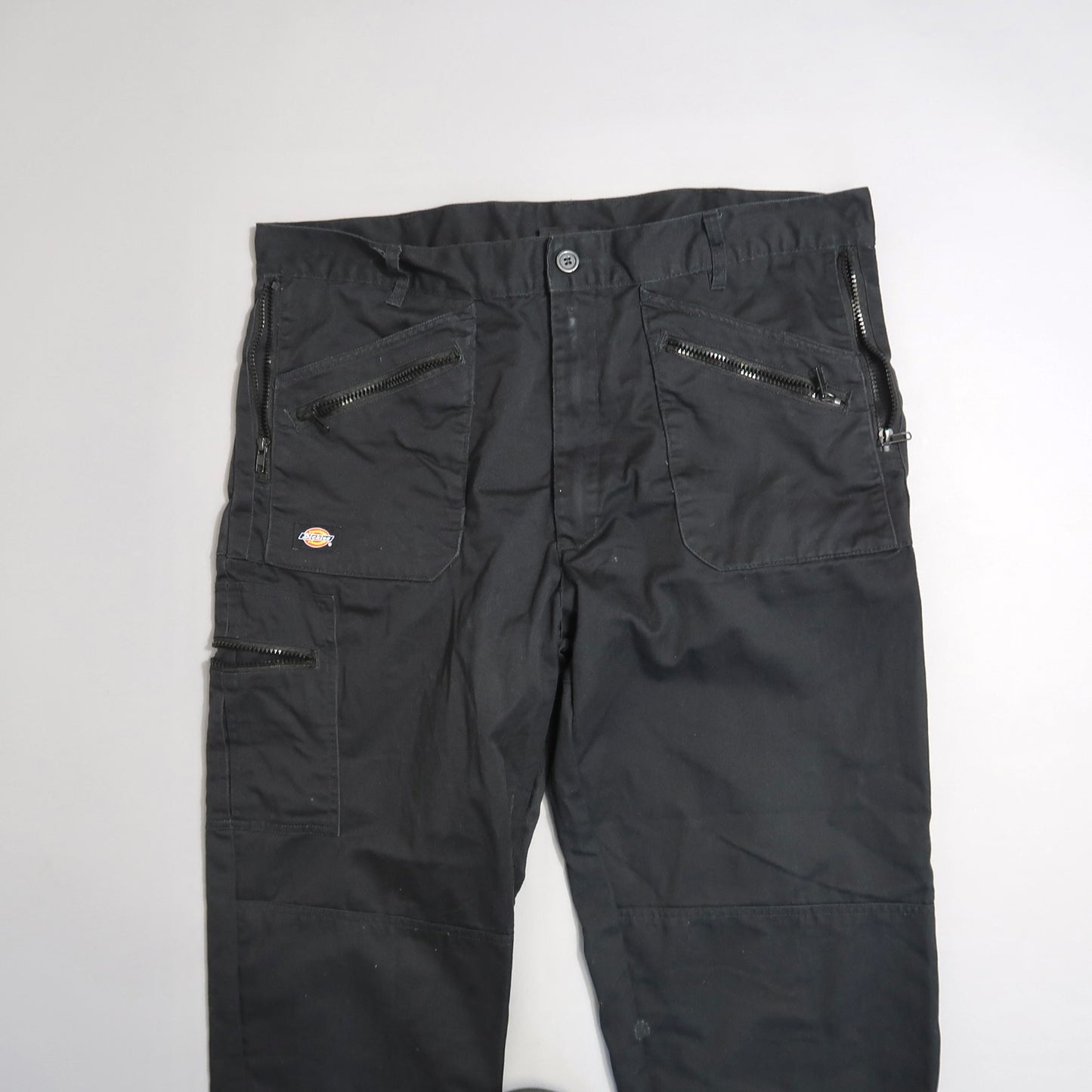 Black cargo pants with multiple zipper pockets on a white background.