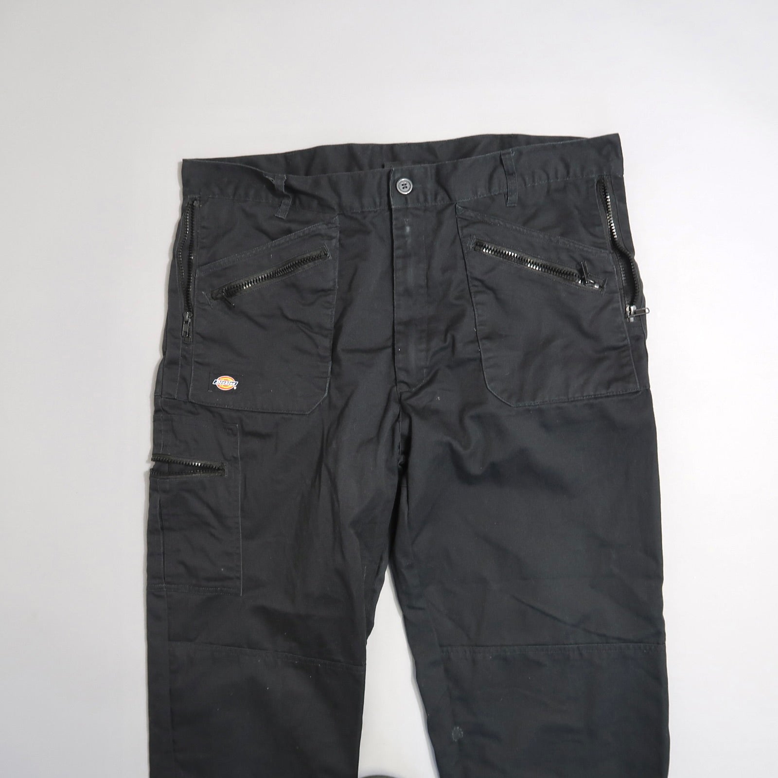Black cargo pants with multiple zipper pockets on a white background.