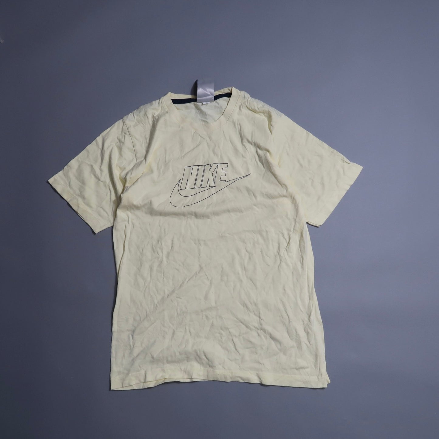 Cream-colored Nike T-shirt on a gray background.