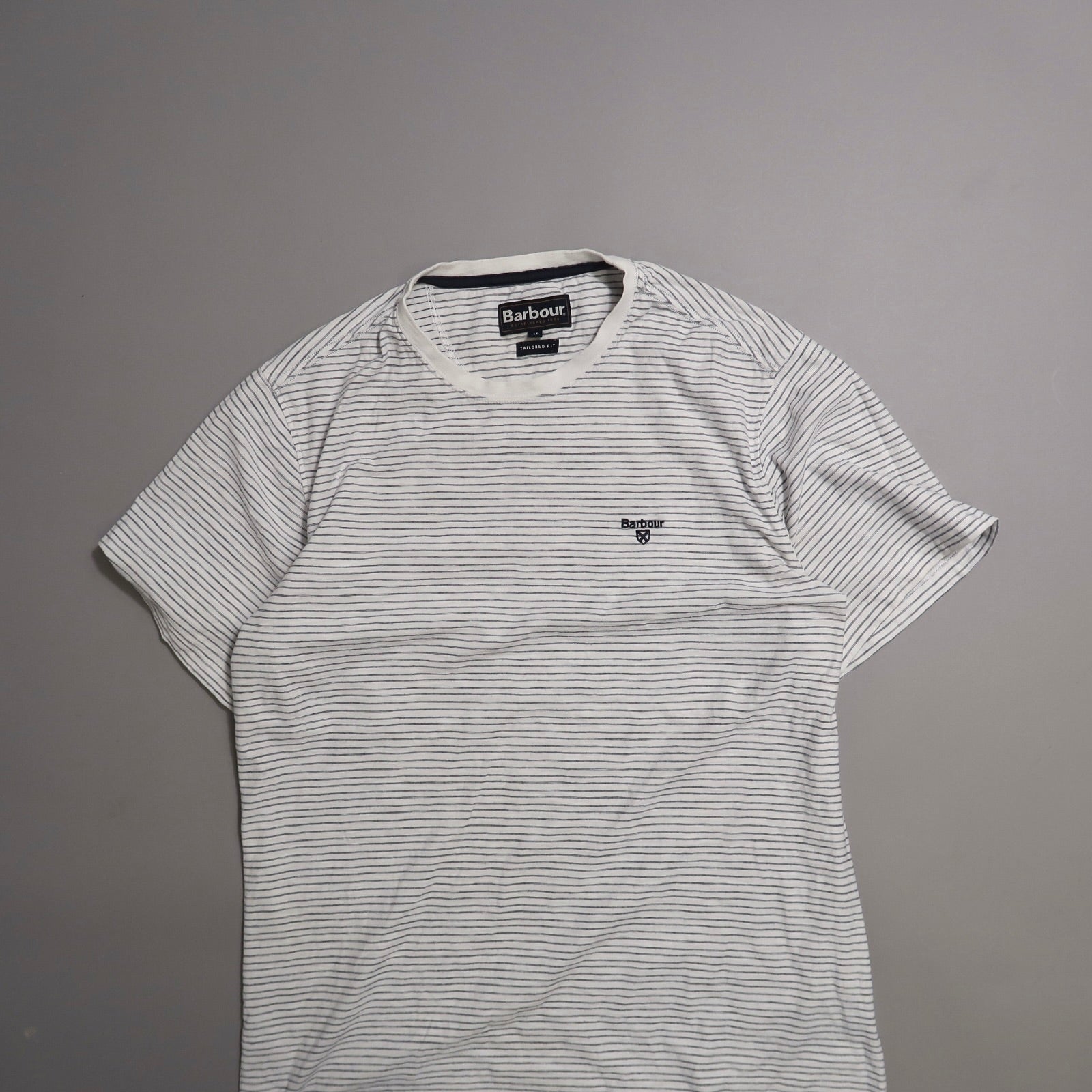 Striped Barbour t-shirt on a gray background.