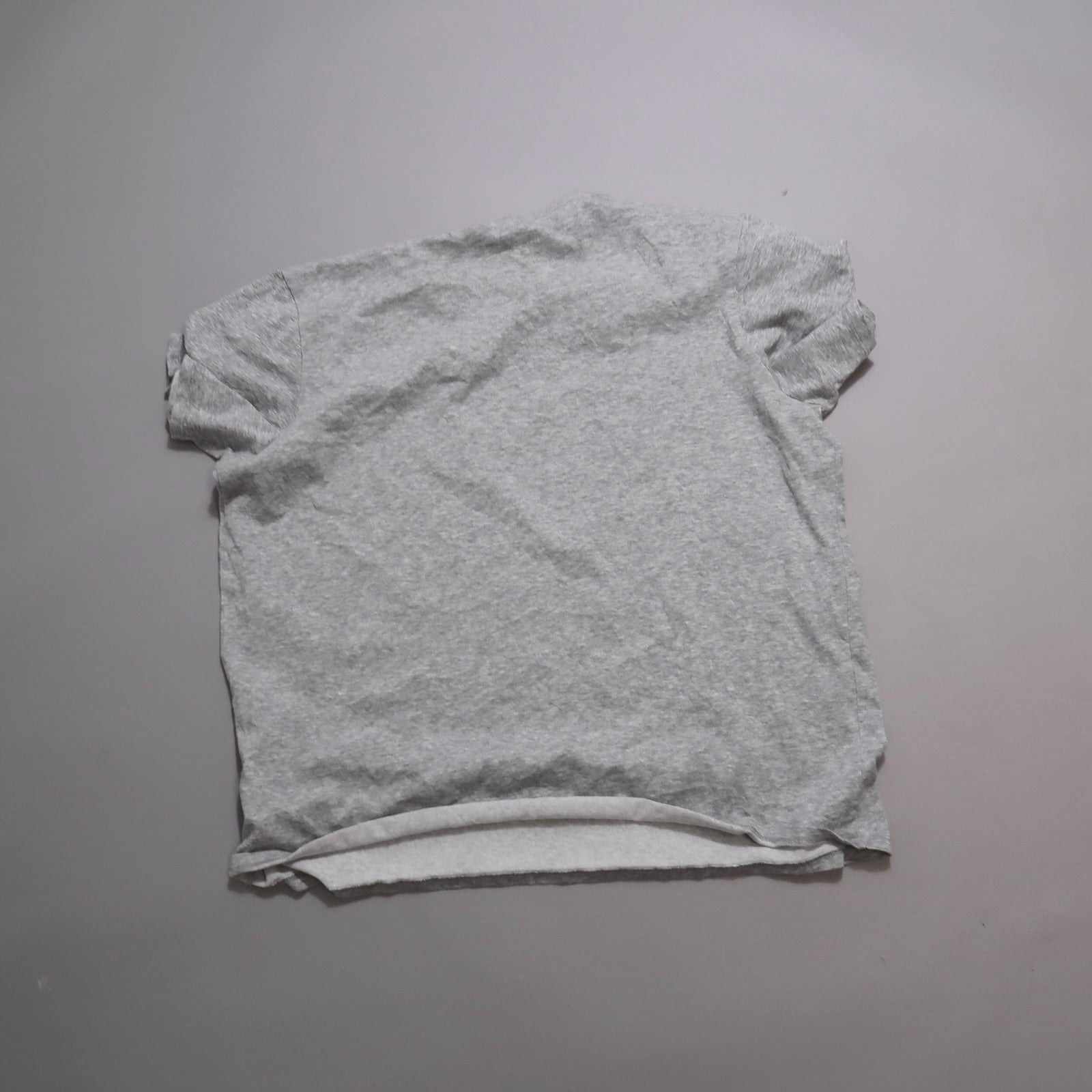 Gray T-shirt laid flat on a plain surface.