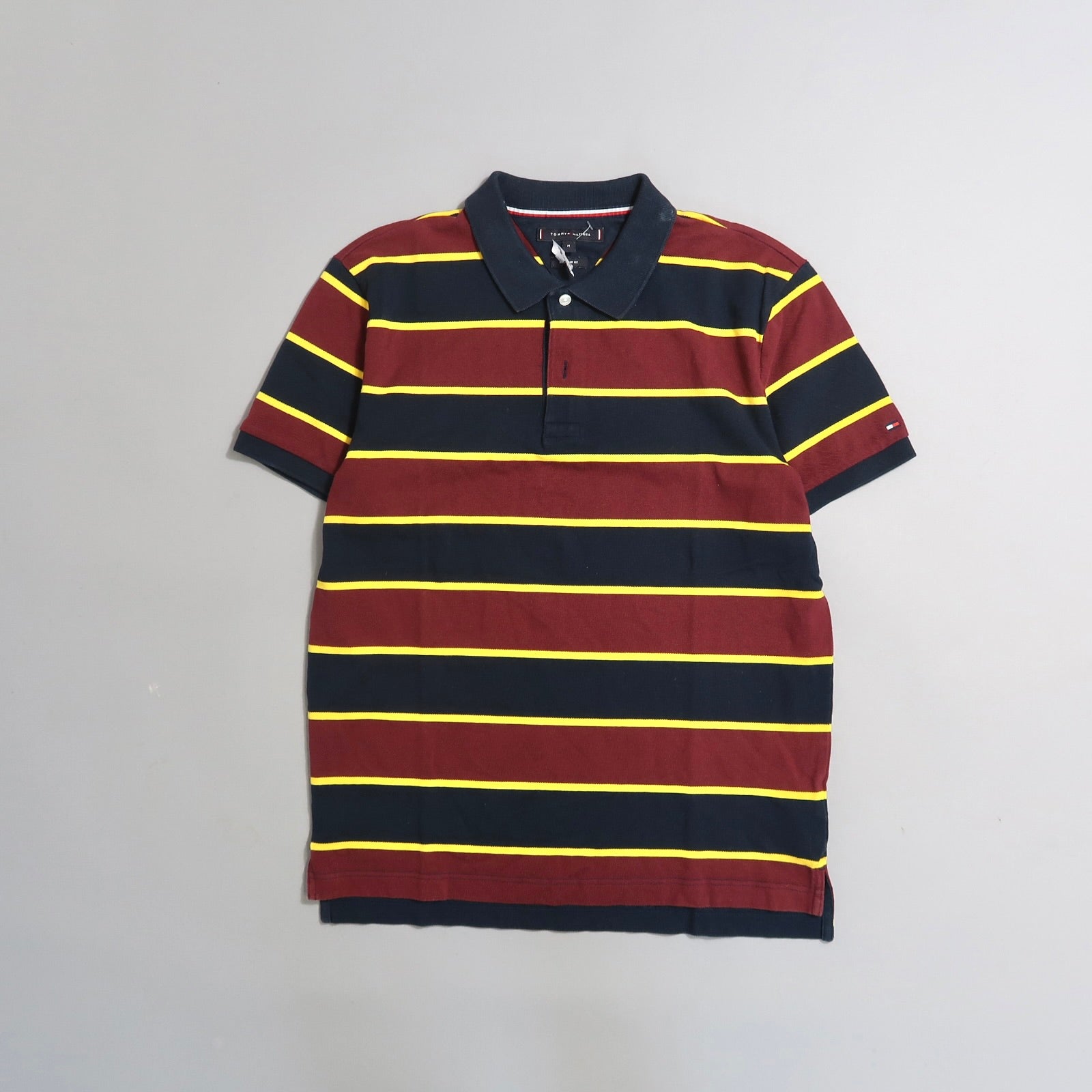 Striped polo shirt with maroon and navy hues, yellow accents.