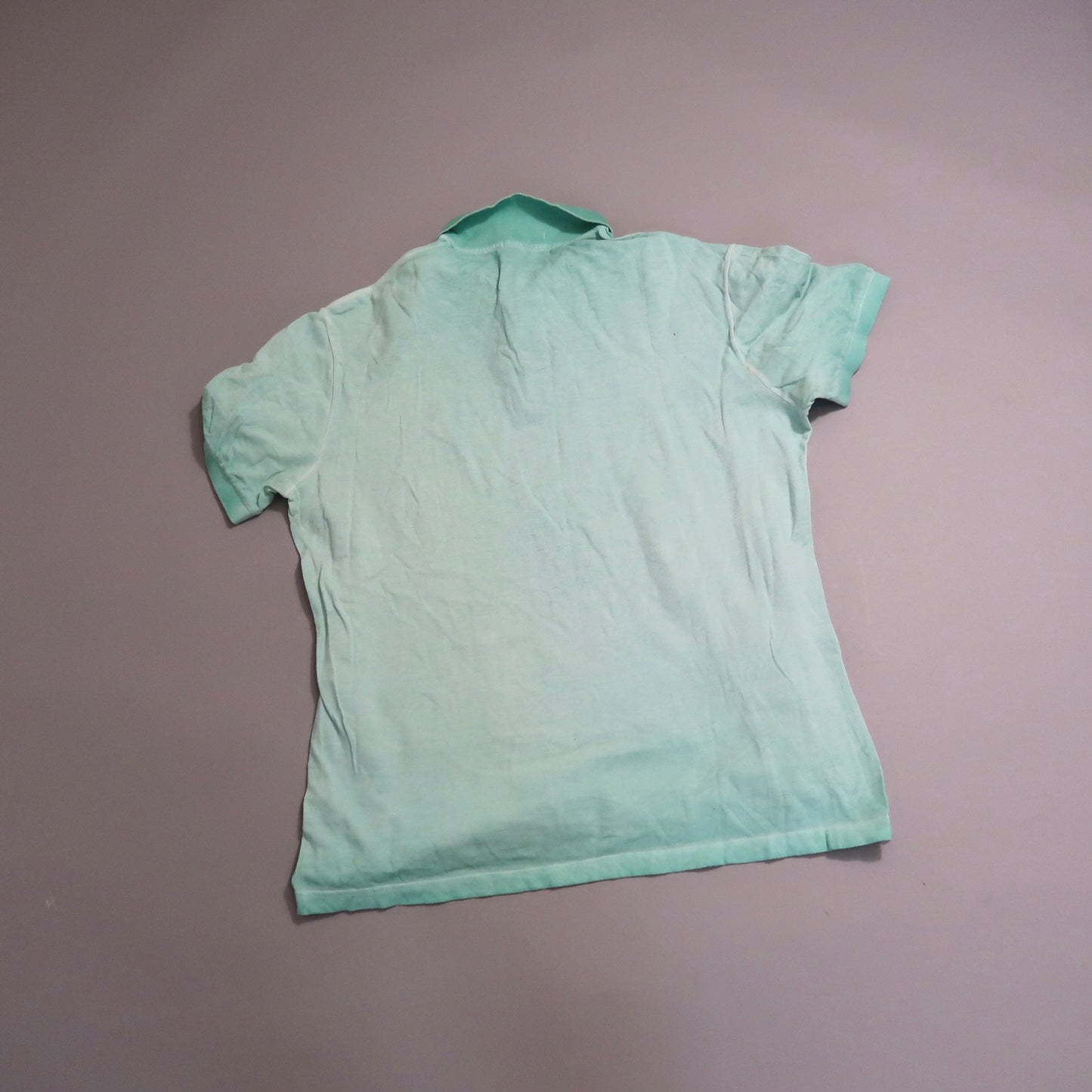 Wrinkled mint-green polo shirt laid flat, back view.