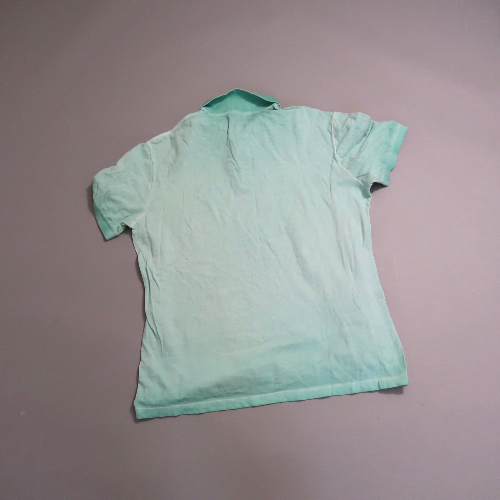 Wrinkled mint-green polo shirt laid flat, back view.