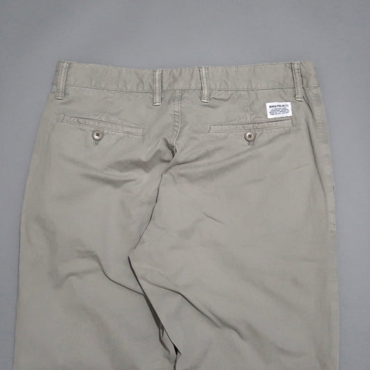 Beige pants with back pockets and a label on the waistband.