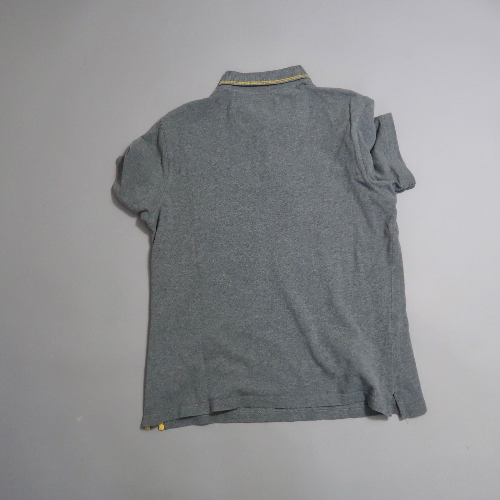 Gray polo shirt with yellow collar detail, laid flat on a surface.
