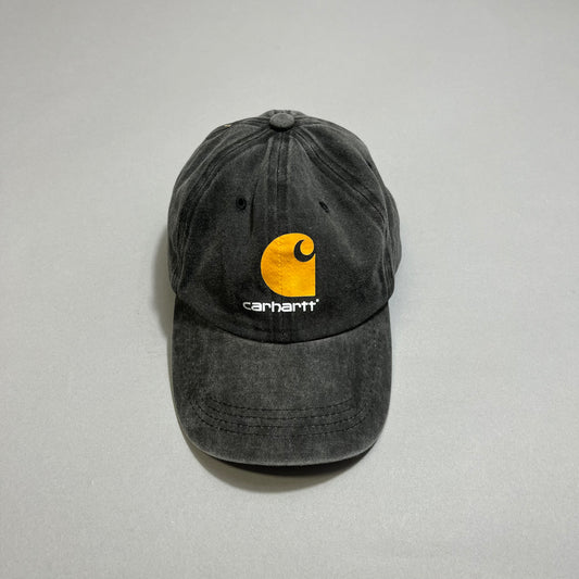 Black Carhartt cap with yellow logo on gray background.