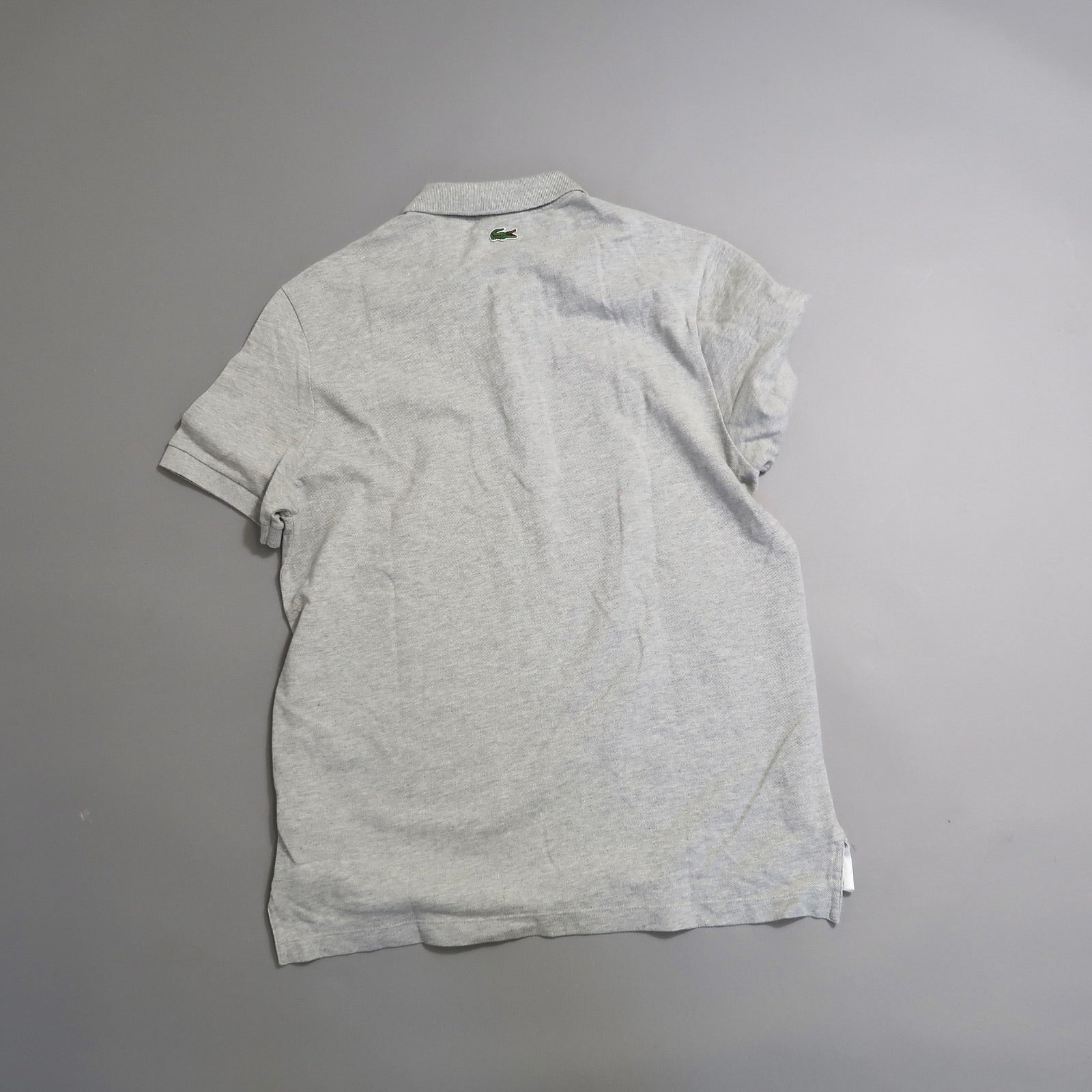Gray polo shirt with logo on the back, laid flat on a surface.