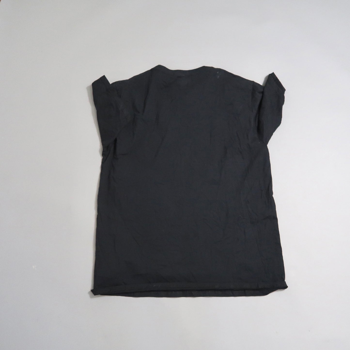 Black wrinkled T-shirt laid flat on a light surface.