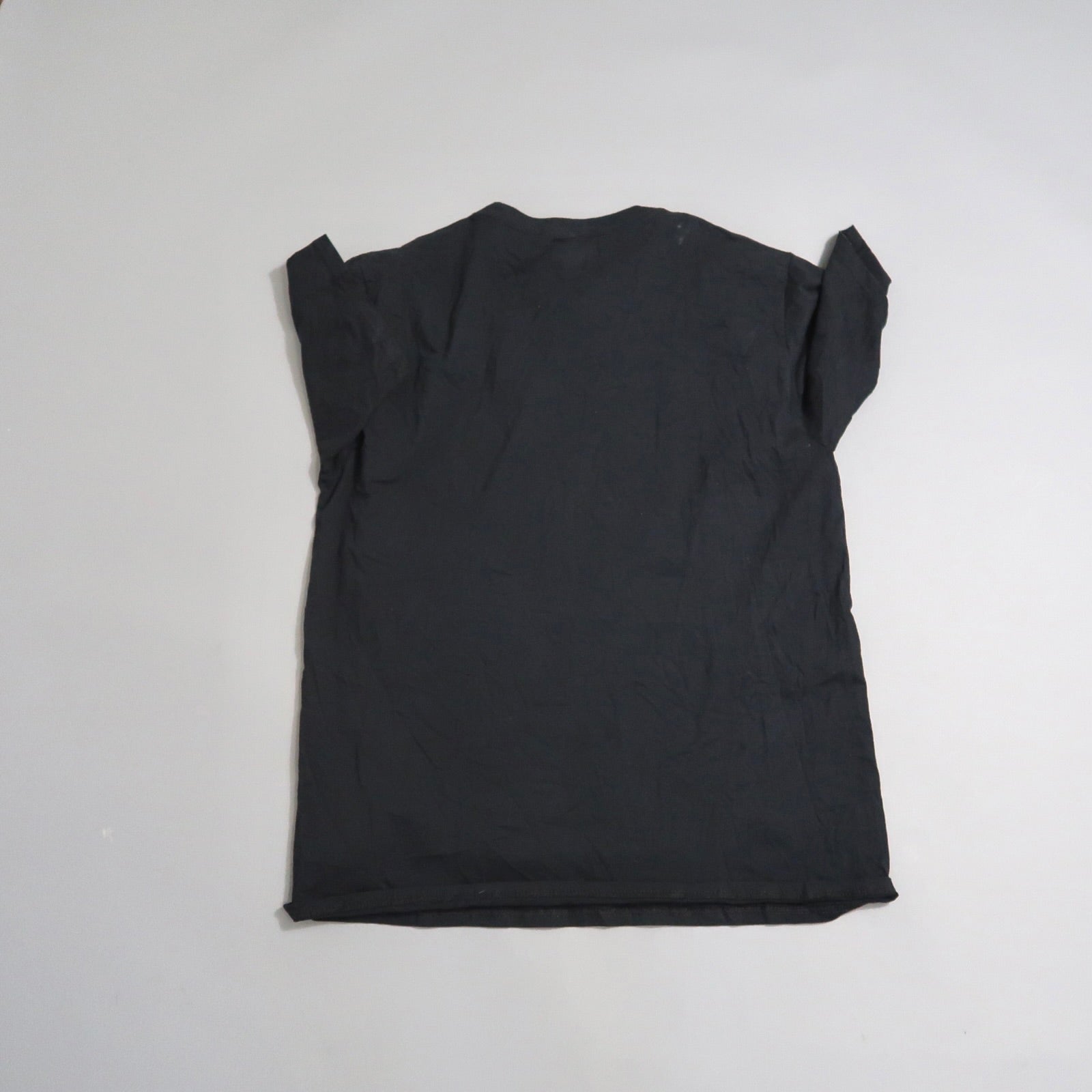 Black wrinkled T-shirt laid flat on a light surface.