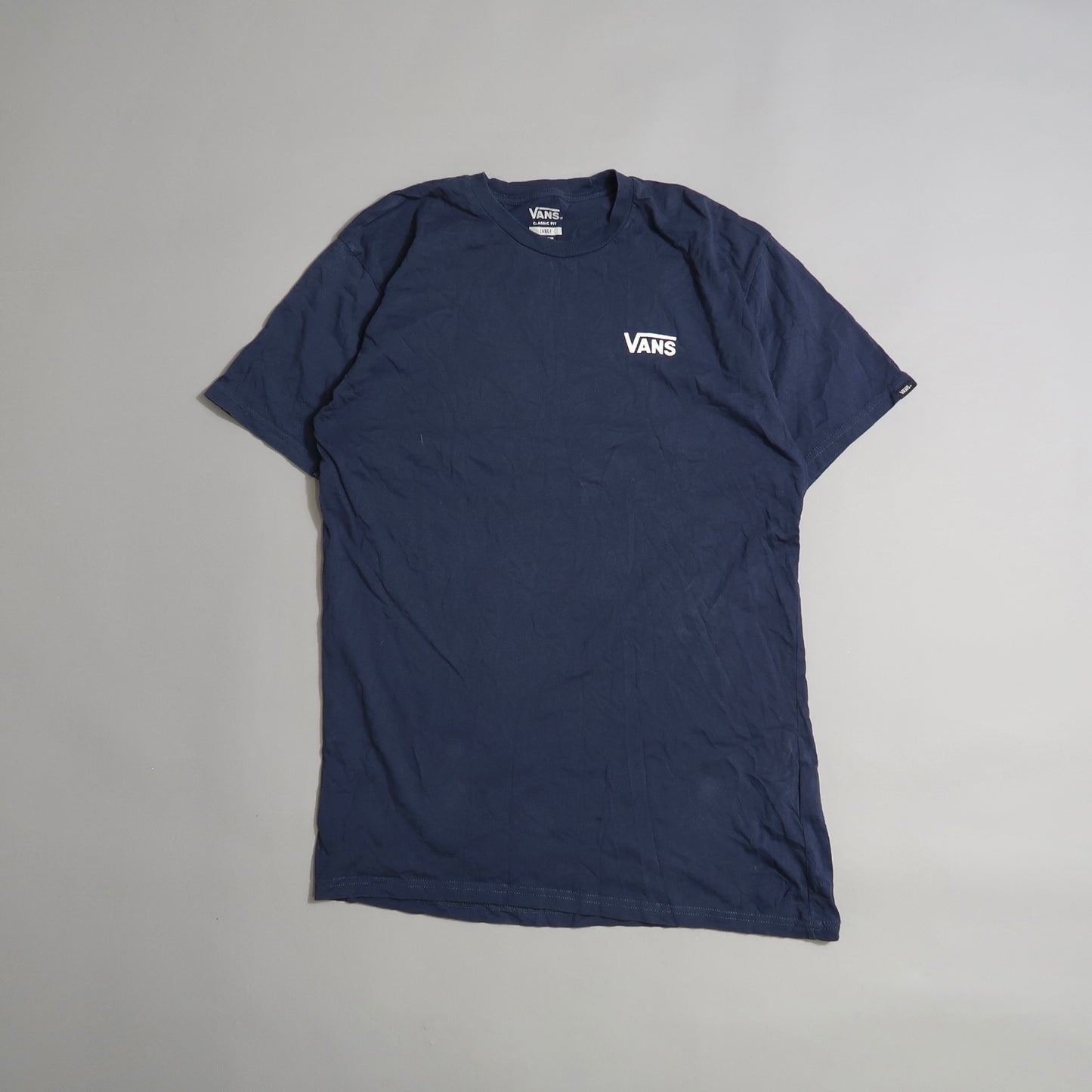 Navy blue Vans t-shirt on a gray background.