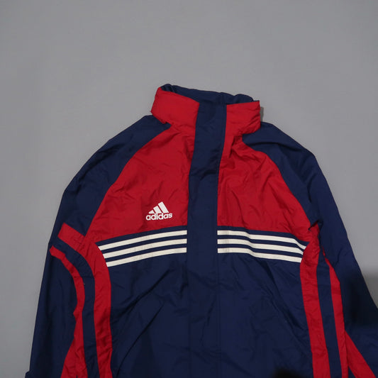 Red and navy Adidas jacket with white stripes on a gray background.