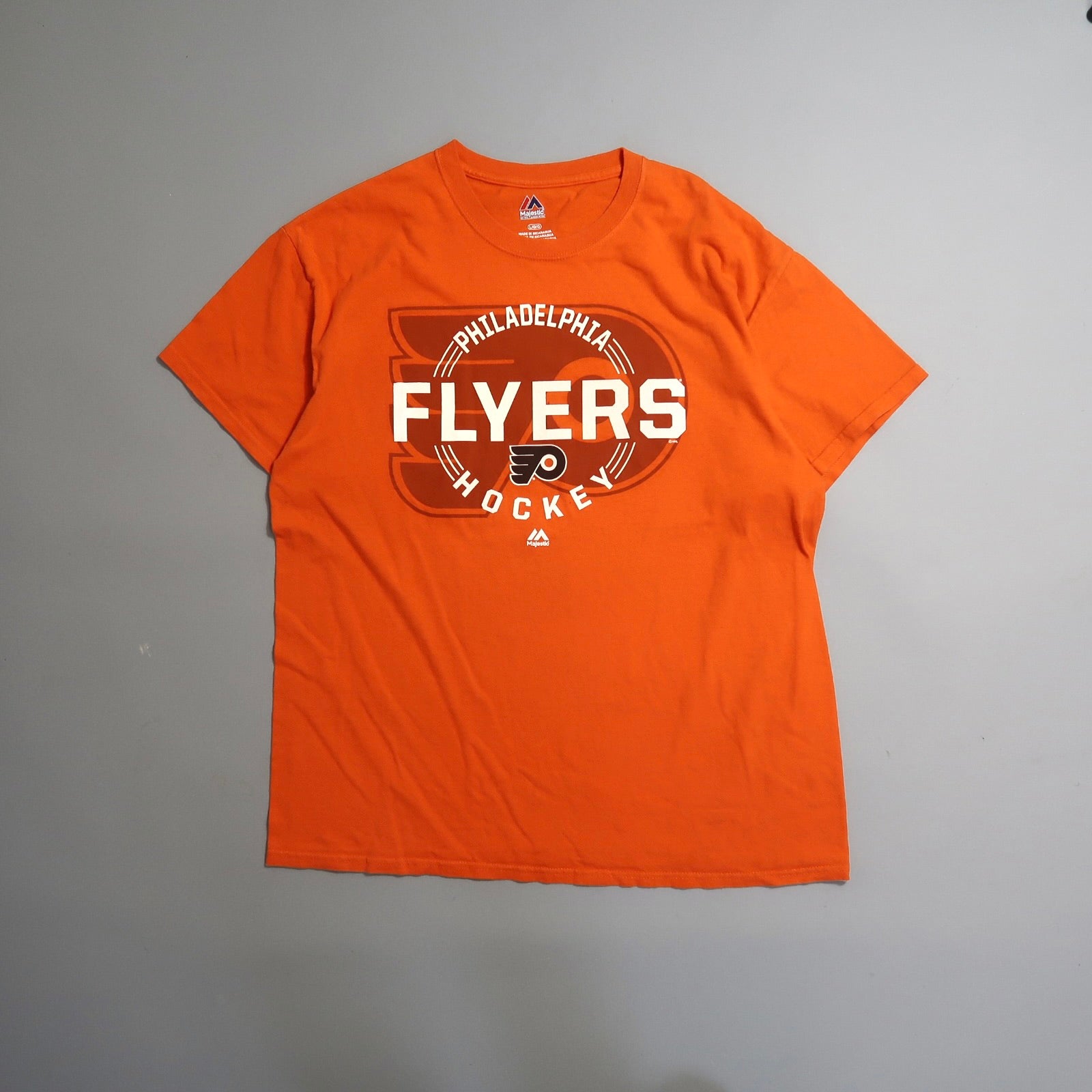 Orange Philadelphia Flyers hockey T-shirt on a gray background.