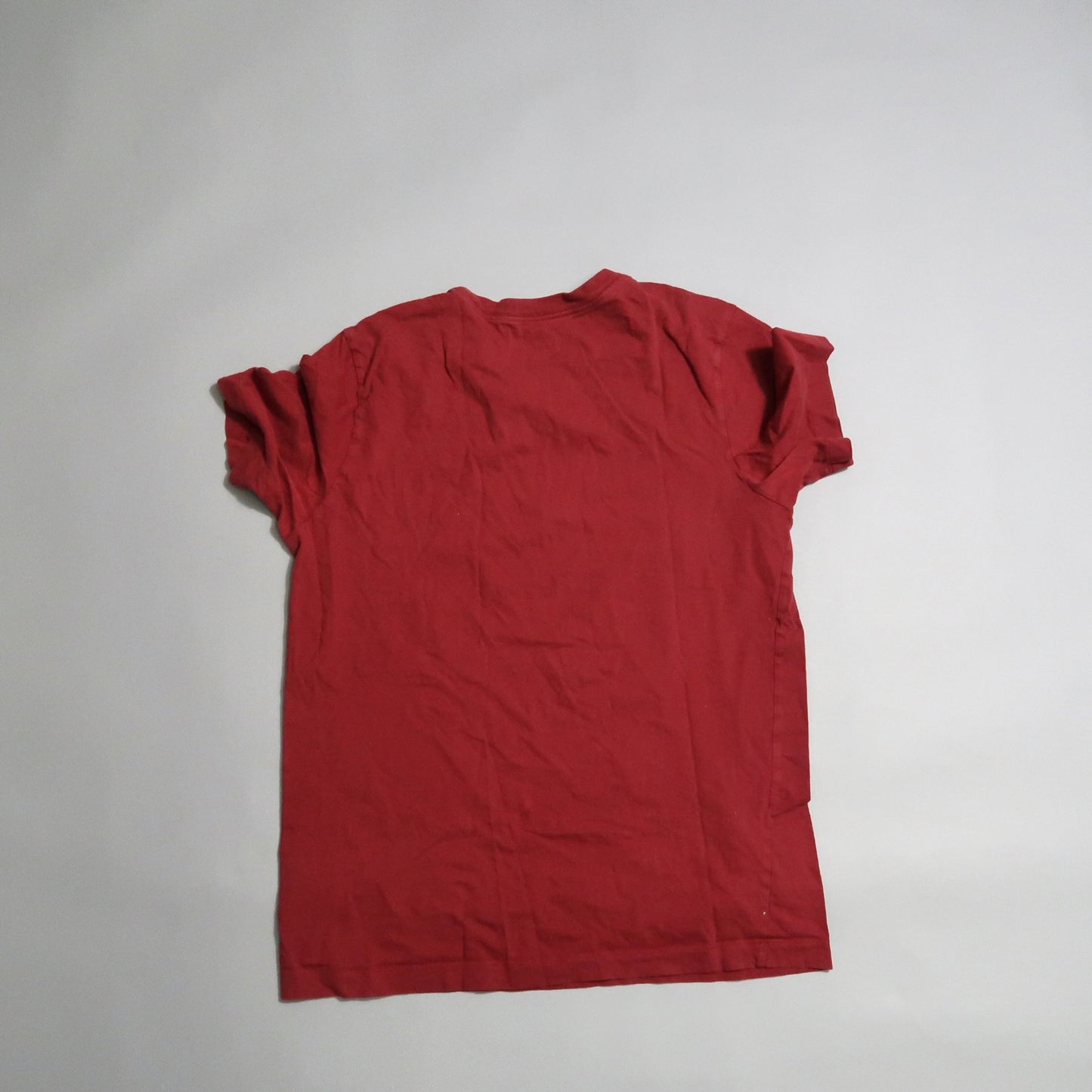 Red t-shirt laying flat on a plain surface, viewed from the back.