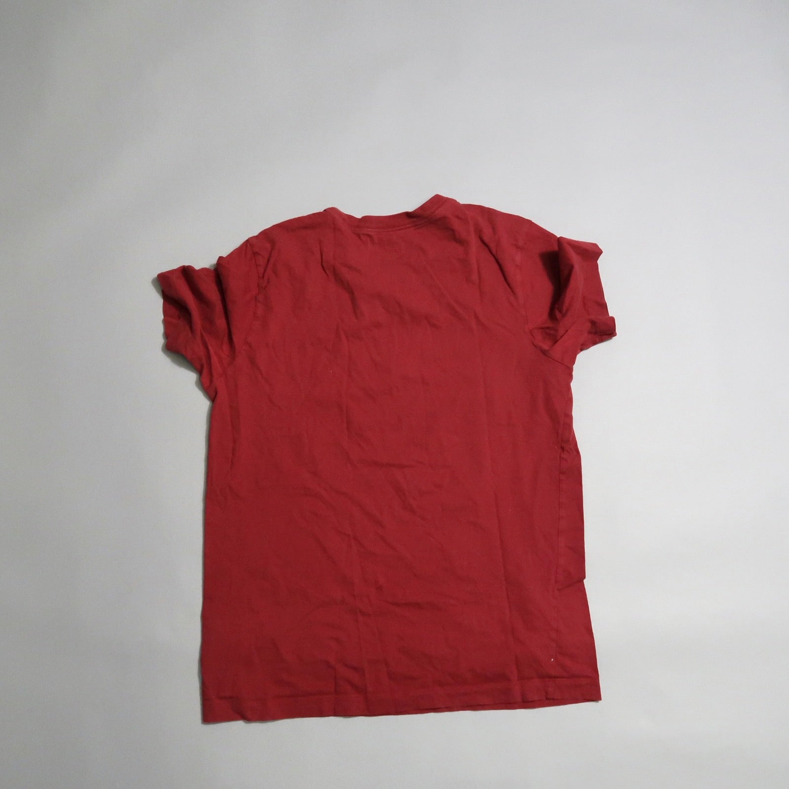 Red t-shirt laying flat on a plain surface, viewed from the back.