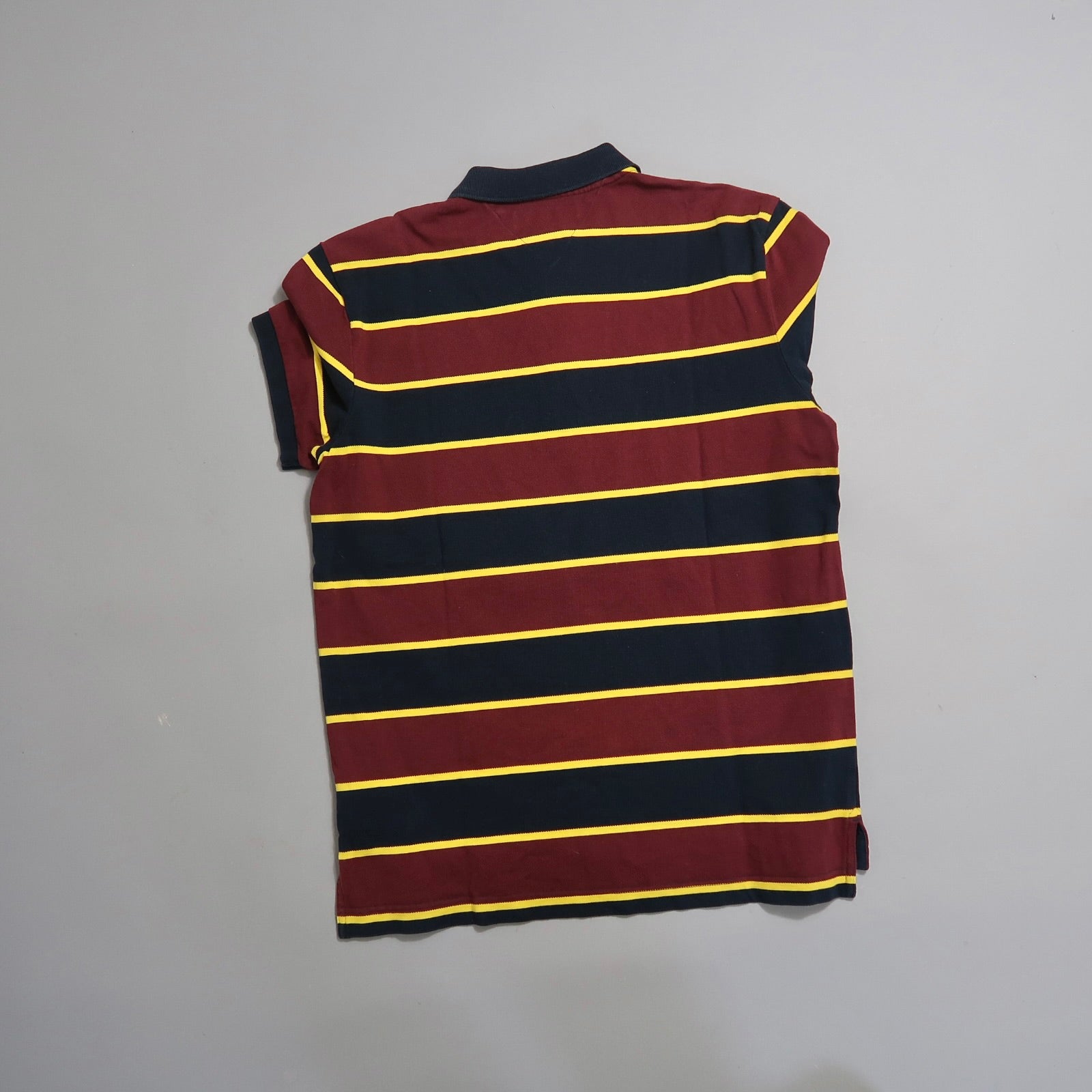 Maroon and navy striped shirt with yellow lines on a flat surface.