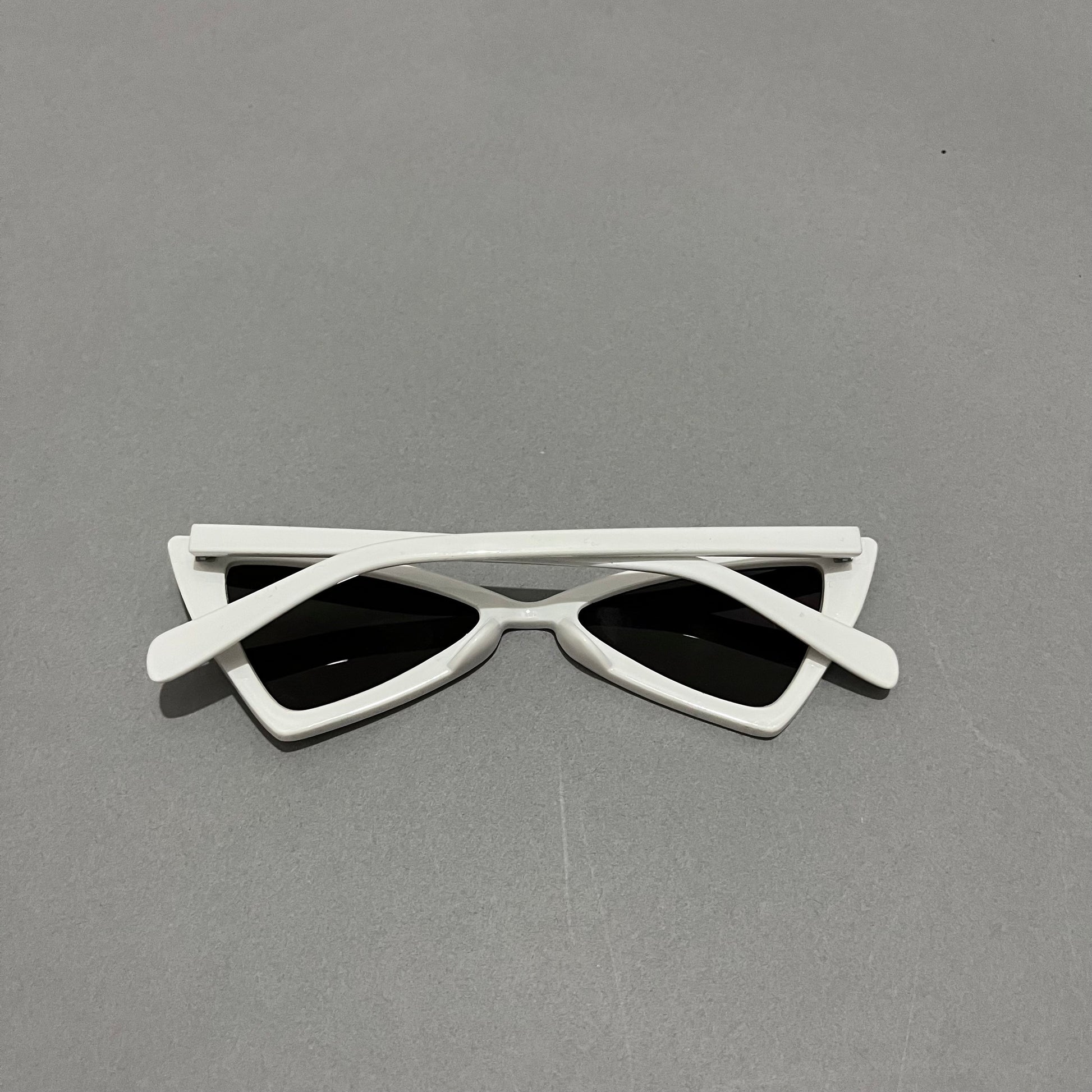 White cat-eye sunglasses on a gray surface.