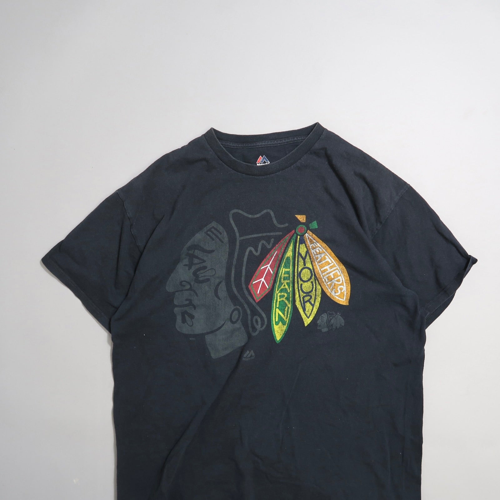 Black T-shirt with colorful feather graphic and abstract face design.