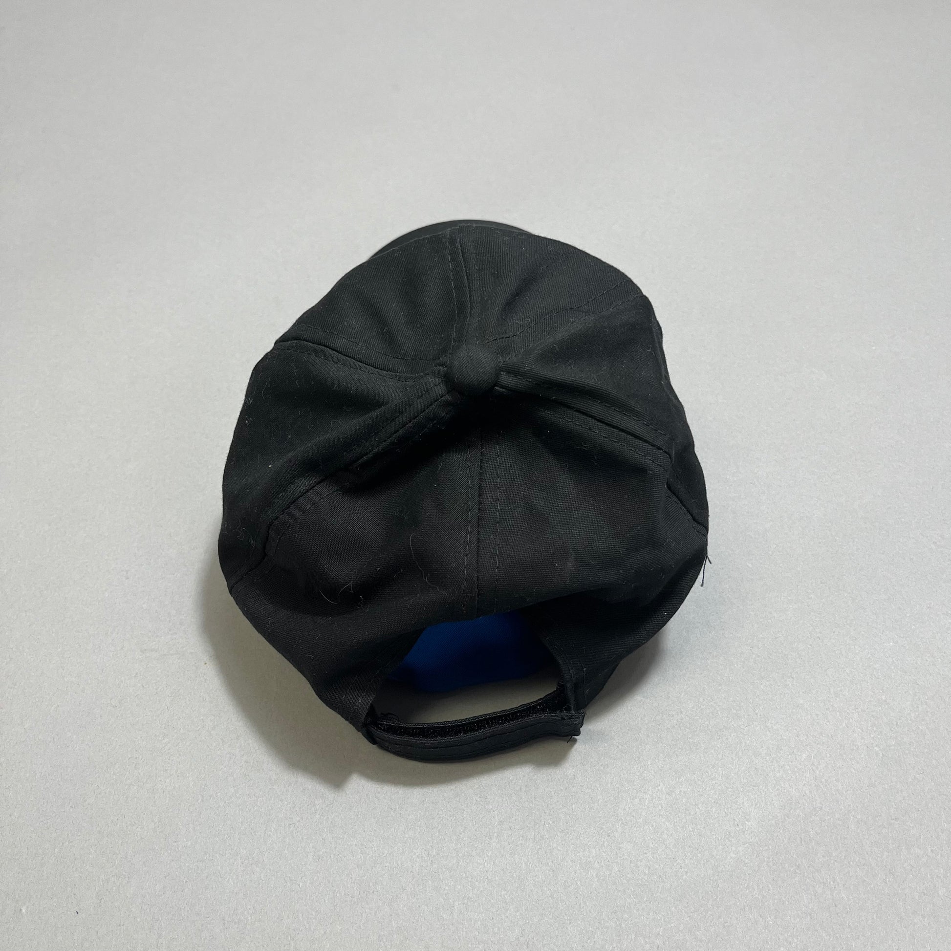 Black cap viewed from the back on a gray surface.