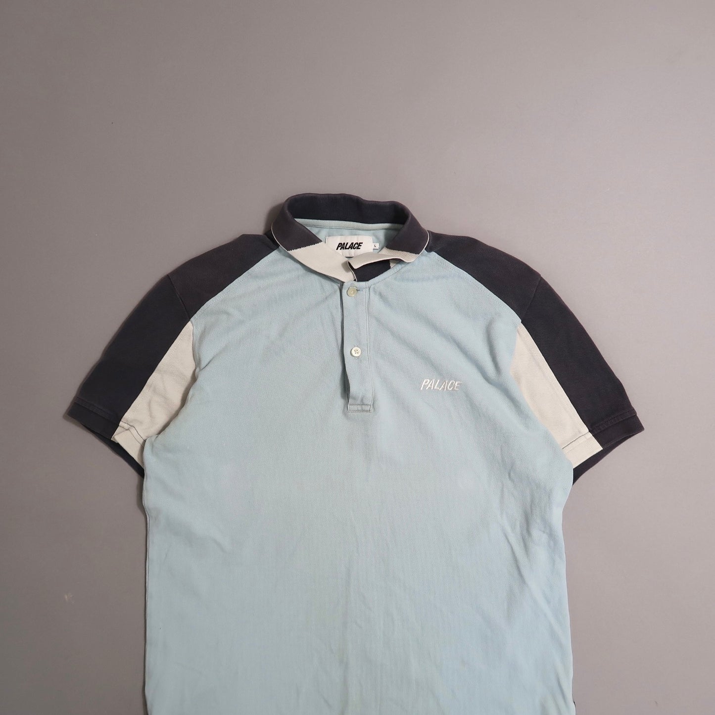 Two-tone polo shirt with nullPalacenull logo on a gray background.