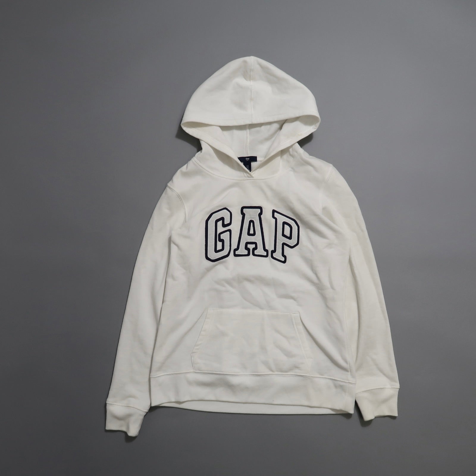 White GAP hoodie on a gray background.
