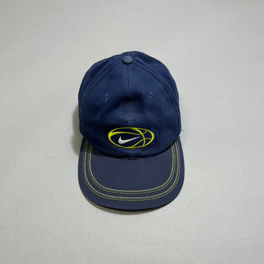 Navy blue cap with yellow logo and stitching on a gray background.