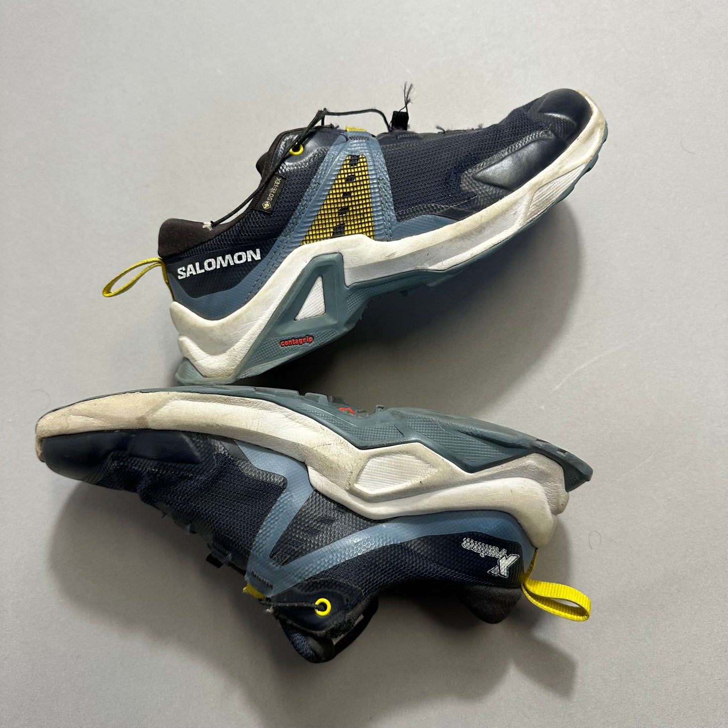 Trail running shoes with yellow and blue accents on a gray background.