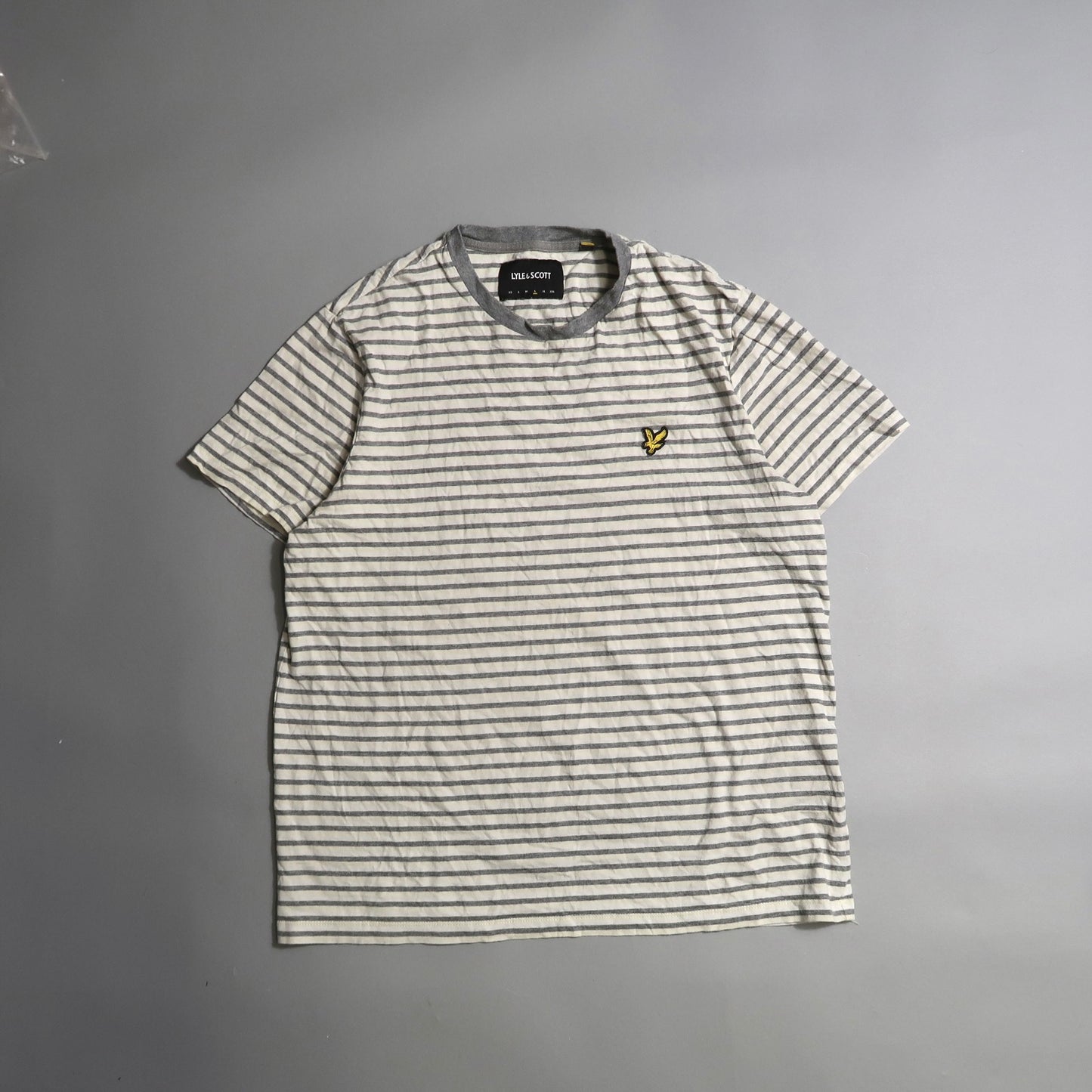 Gray and white striped T-shirt with a small yellow logo on the chest.