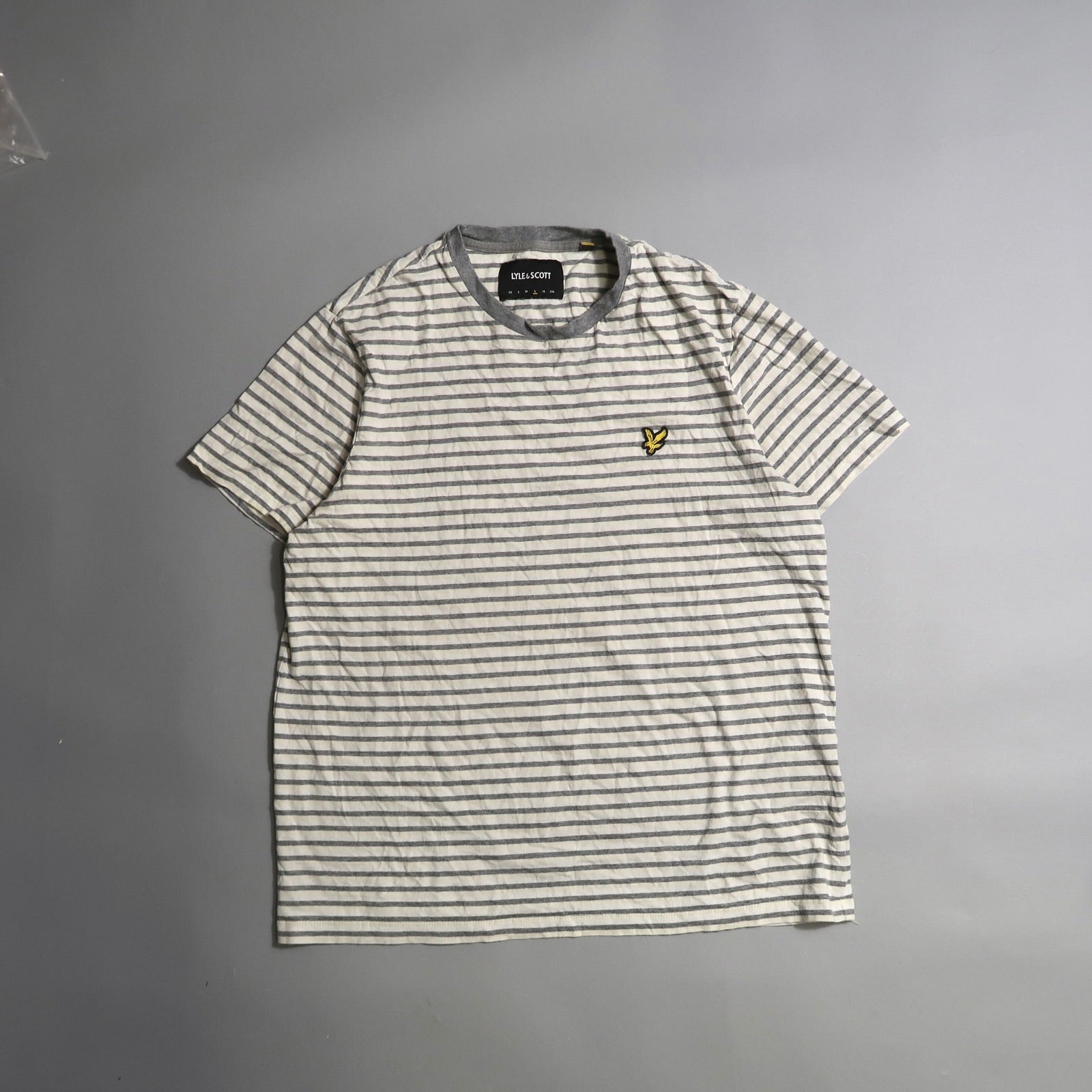 Gray and white striped T-shirt with a small yellow logo on the chest.