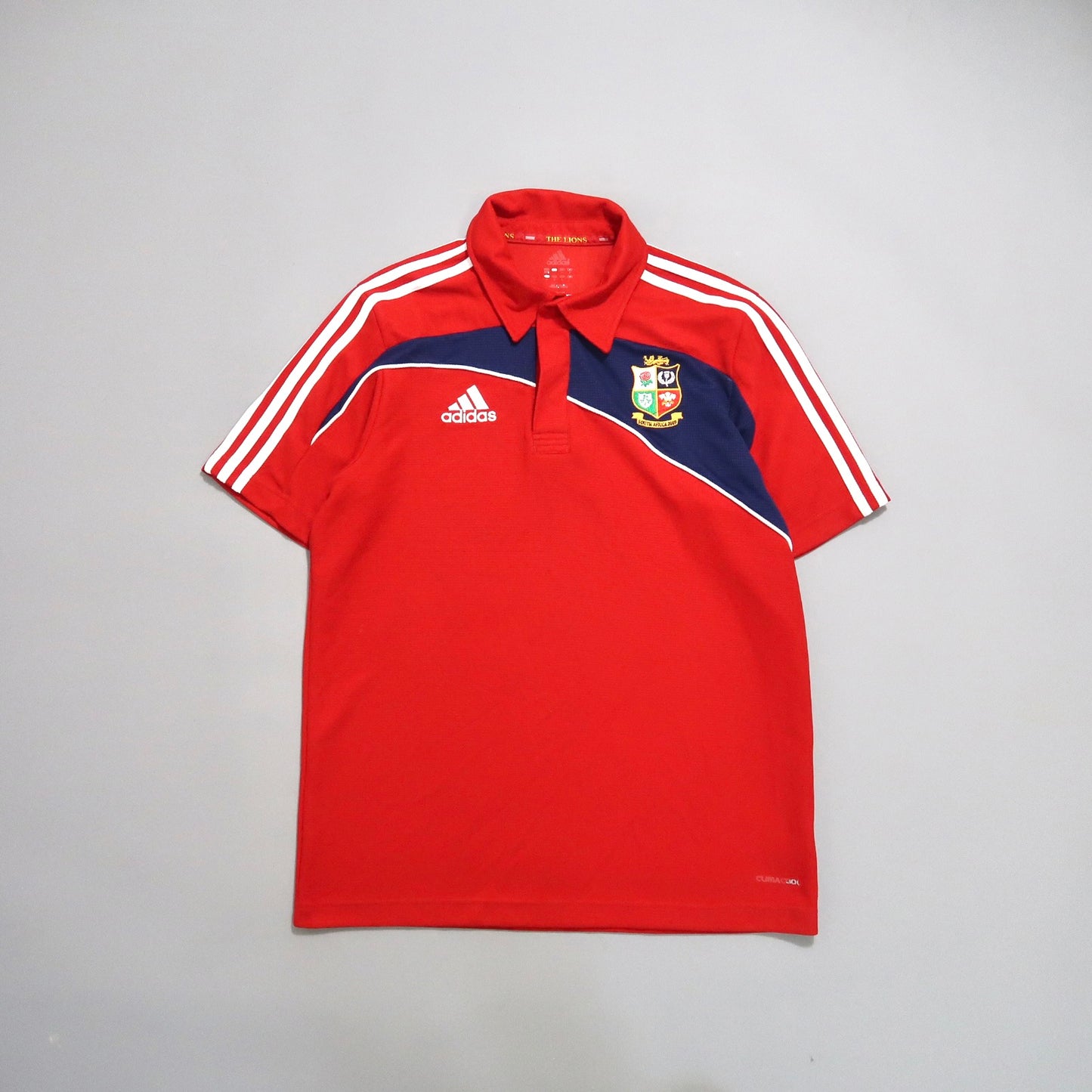 Red Adidas polo with stripes and a sports team crest.